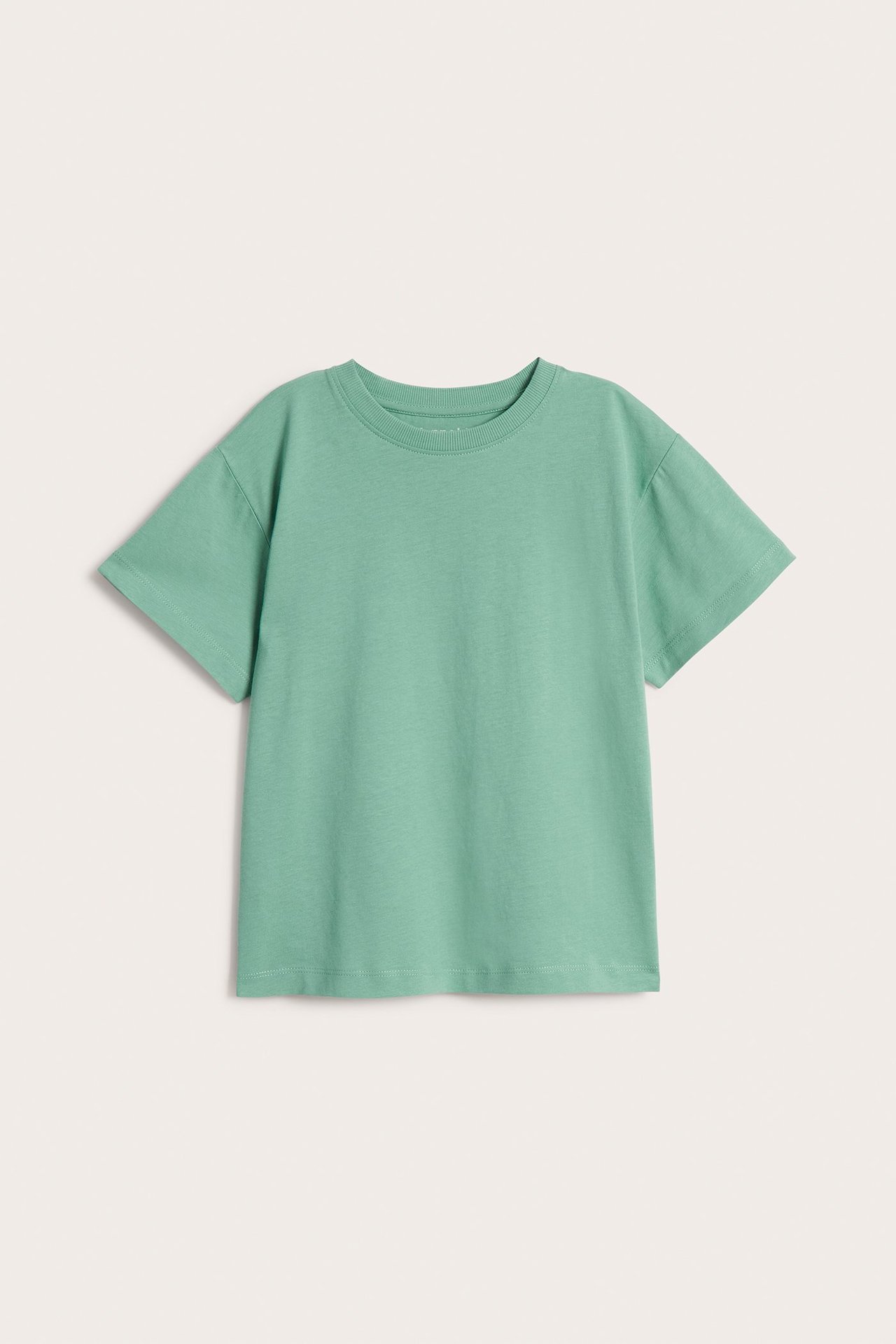 Widok z przodu: zielona, luźna bawełniana koszulka dziecięca z obniżonymi ramionami i prążkowanym dekoltem.
