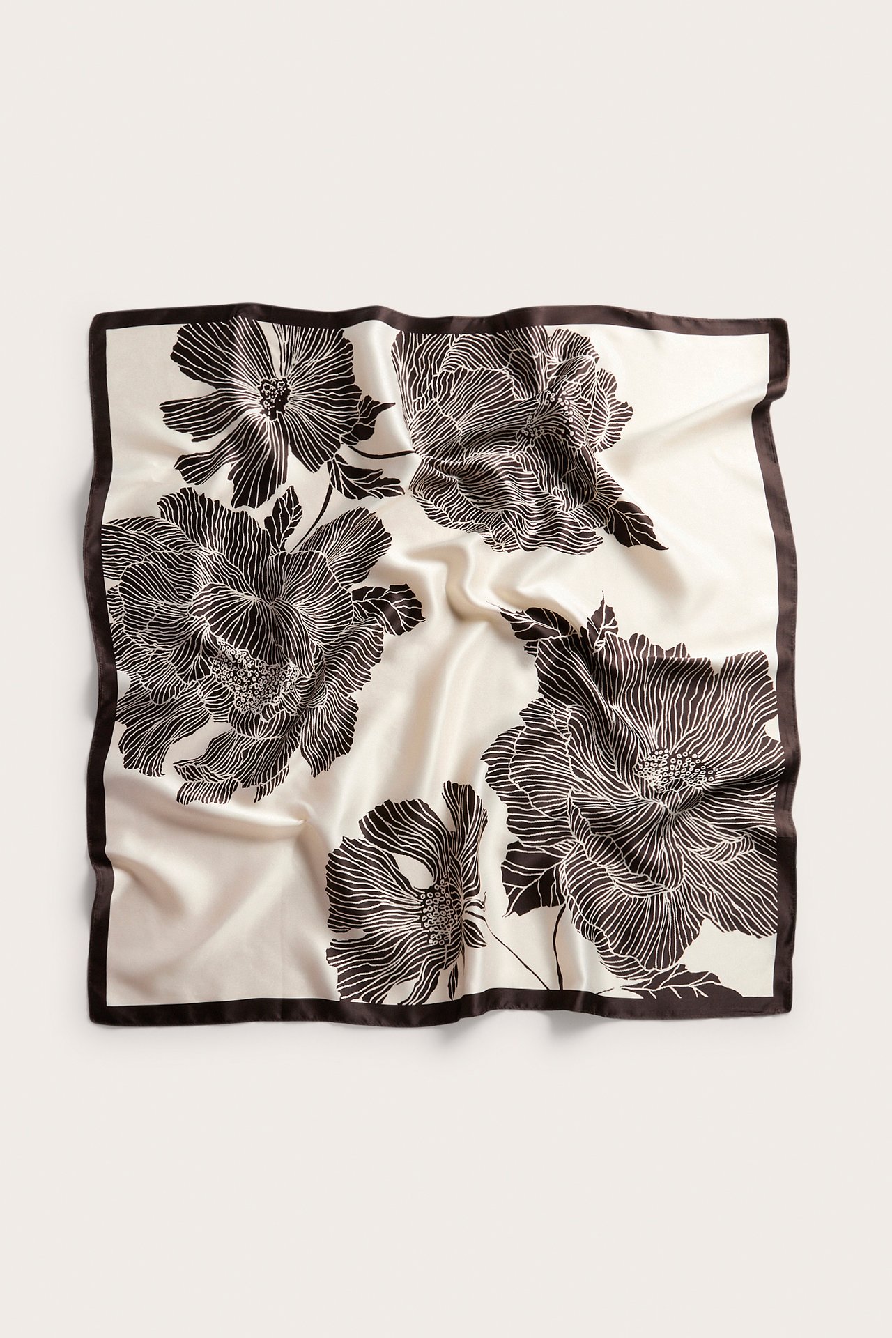 Ylhäältä kuvattu neliönmuotoinen vaalea polyesterihuivi tummanruskealla kukka-aiheisella kuviolla ja reunalla.