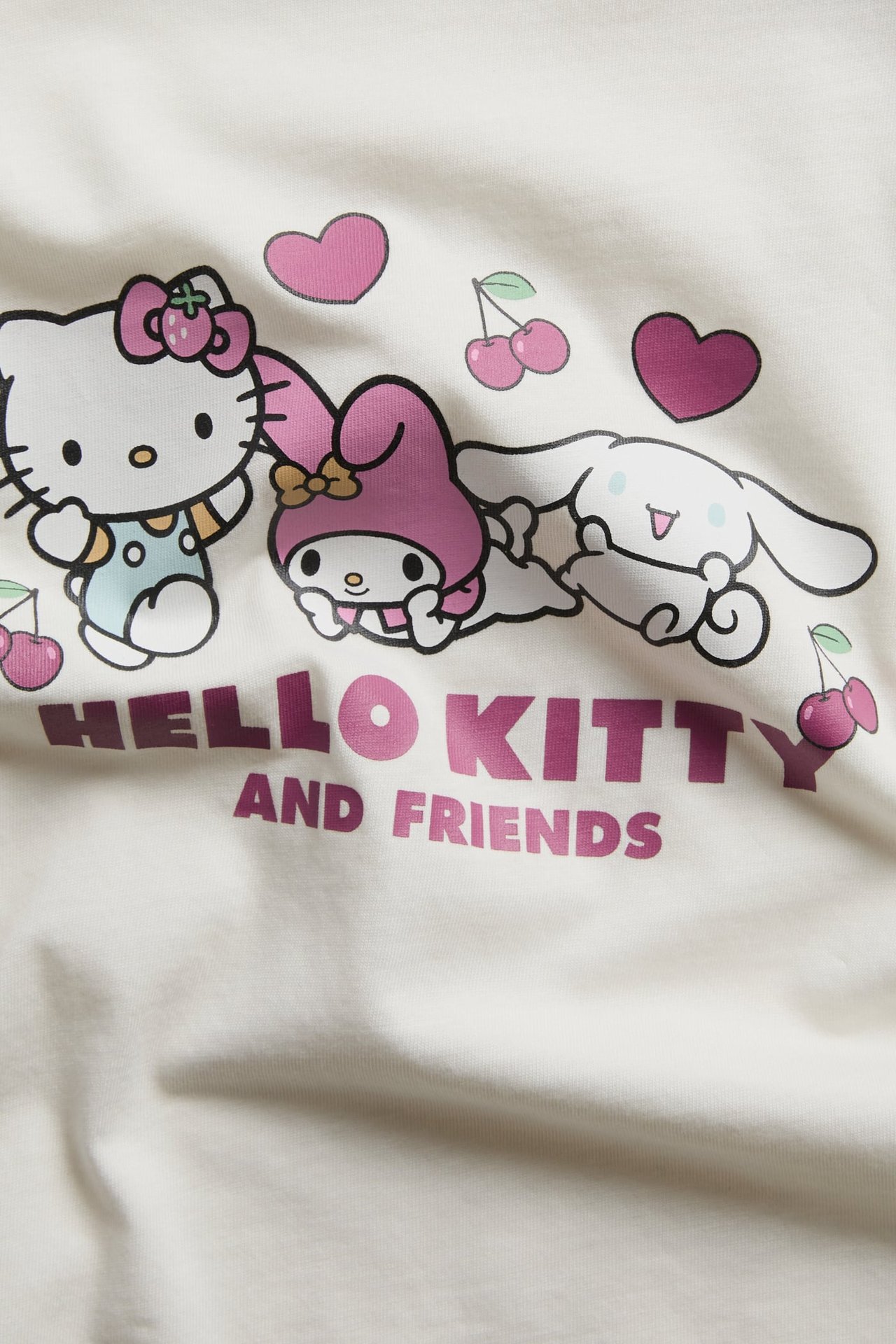 Zbliżenie na biały top z nadrukiem postaci 'Hello Kitty and Friends'.