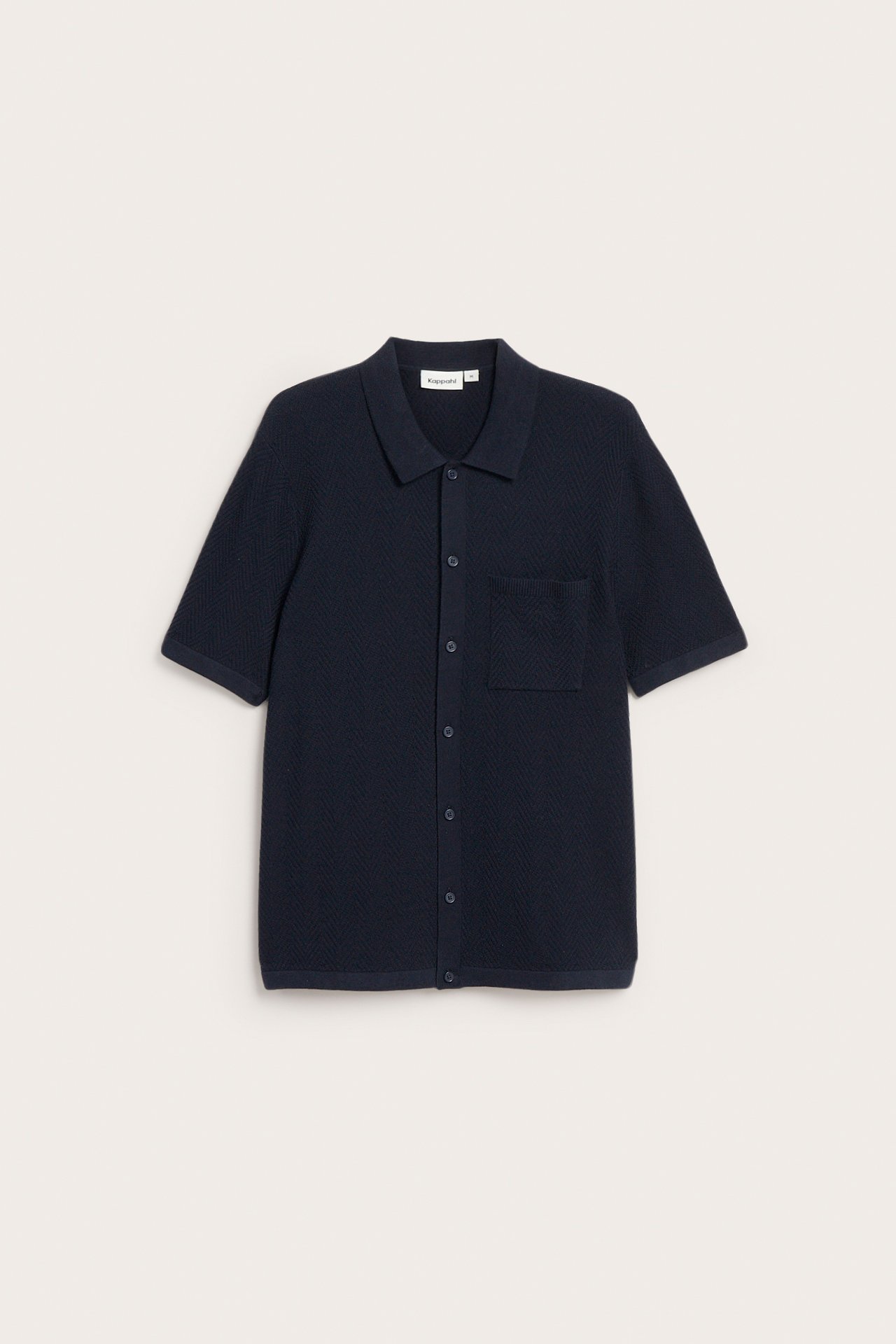 Framifrån: Mörkblå stickad kortärmad pikétröja med textur, bröstficka och hel knappslå.