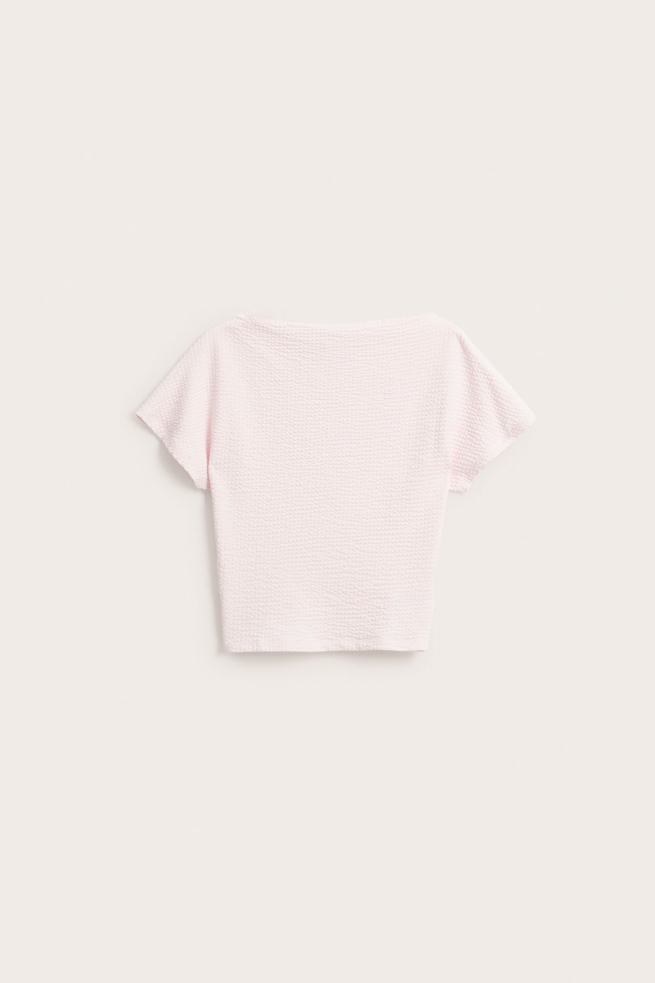 Framifrån: Ljusrosa kortärmad topp i bäckebölja med båthals och fladdermusärm.