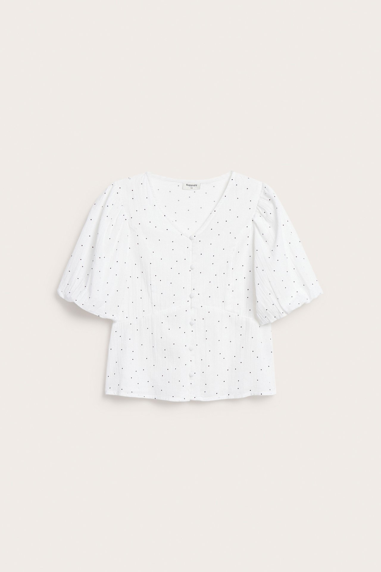 Frontvy av en vit blus med svarta prickar, puffärmar, V-ringning och klädda knappar.