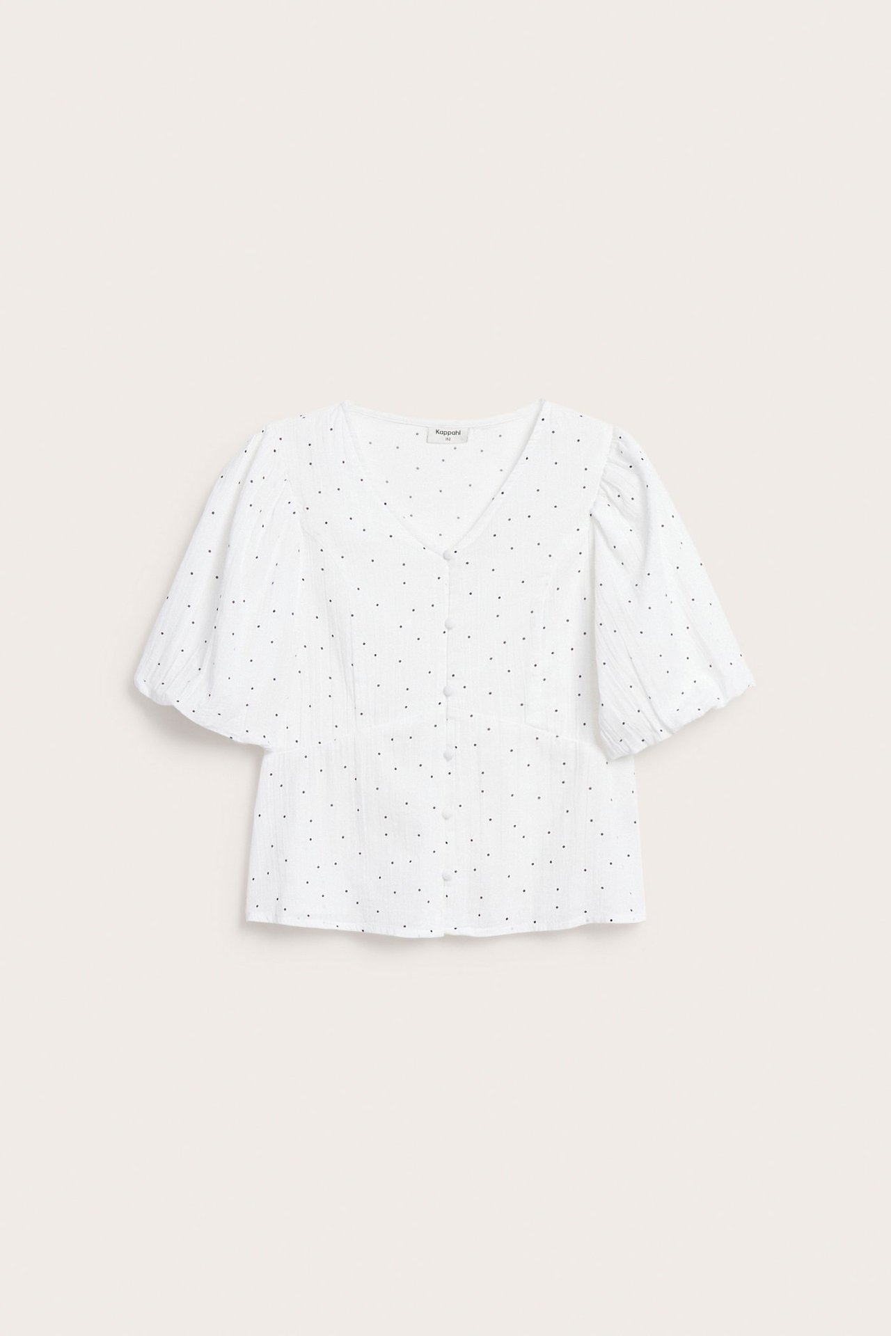 Edestä näkymä valkoisesta pisteellisestä puserosta, jossa on pussihihat, V-pääntie ja päällystetyt napit.
