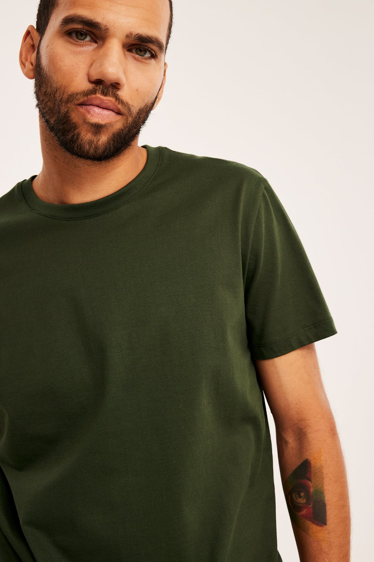 Framsida av en man i en enfärgad mörkgrön kortärmad t-shirt med rund hals.