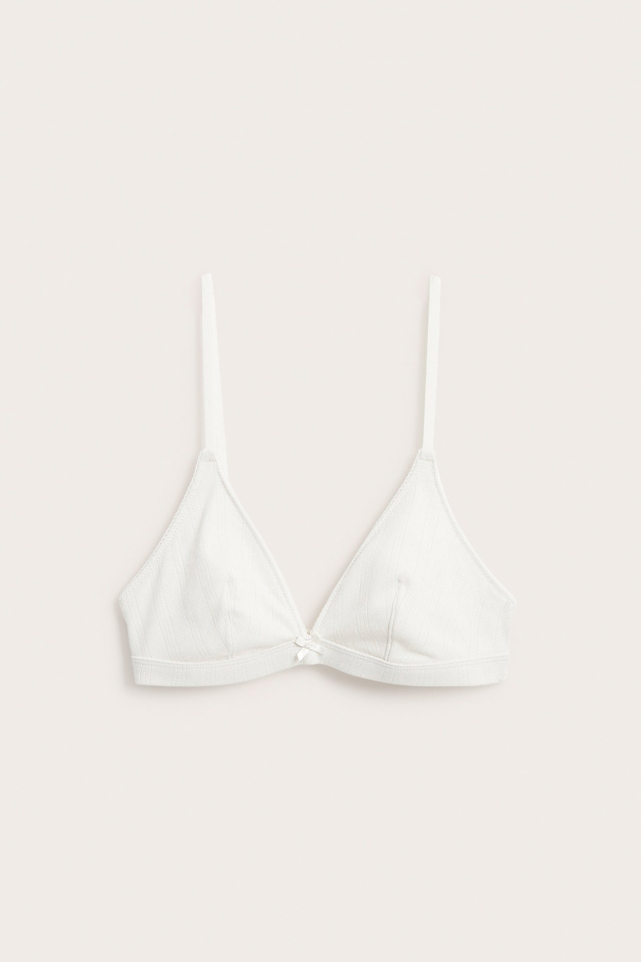 Edestä, luonnonvalkoinen pointelle-puuvillabralette, jossa on kolmiokupit ja pieni rusetti.