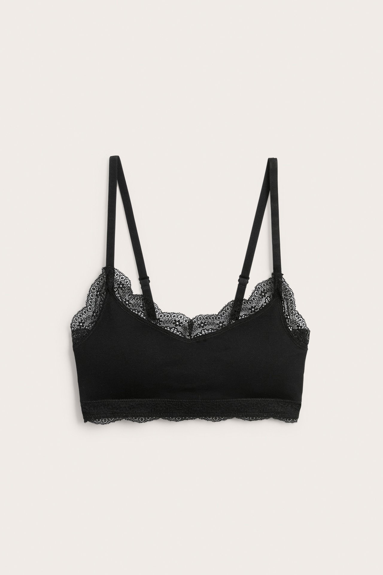 Svart bralette med spetsdetaljer och justerbara axelband, framifrån.