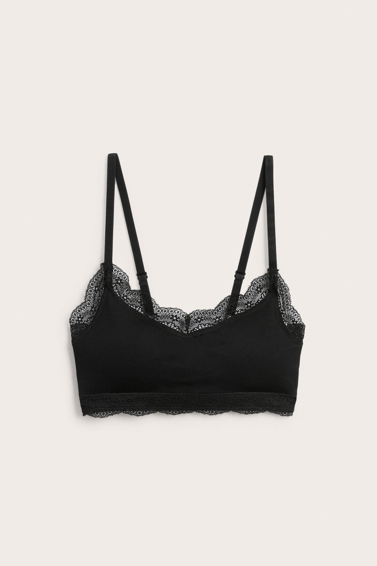 Svart bralette med spetsdetaljer och justerbara axelband, framifrån.