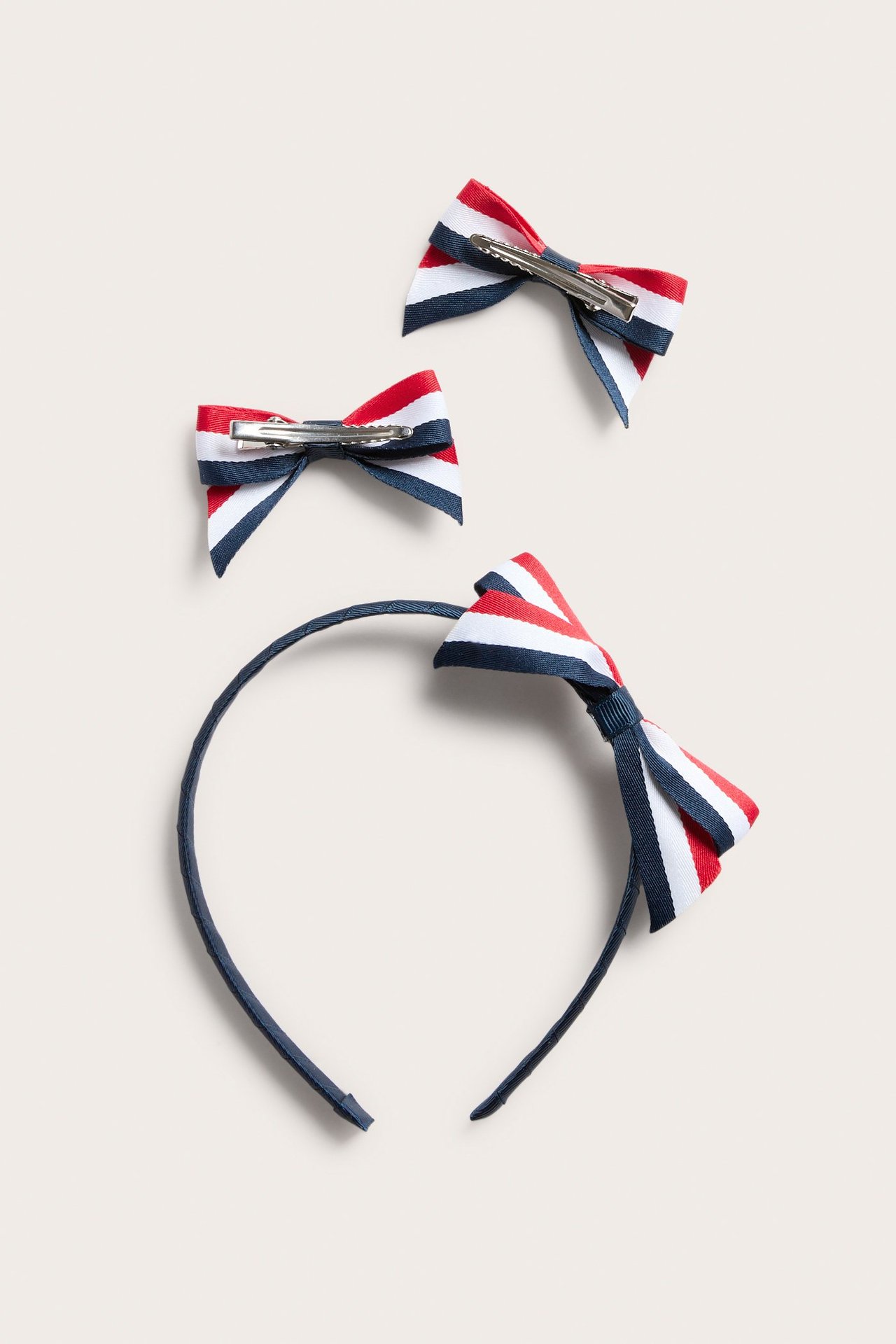 Widok z góry na ciemnoniebieską opaskę z czerwoną, białą, niebieską kokardą w paski i dwie pasujące spinki.