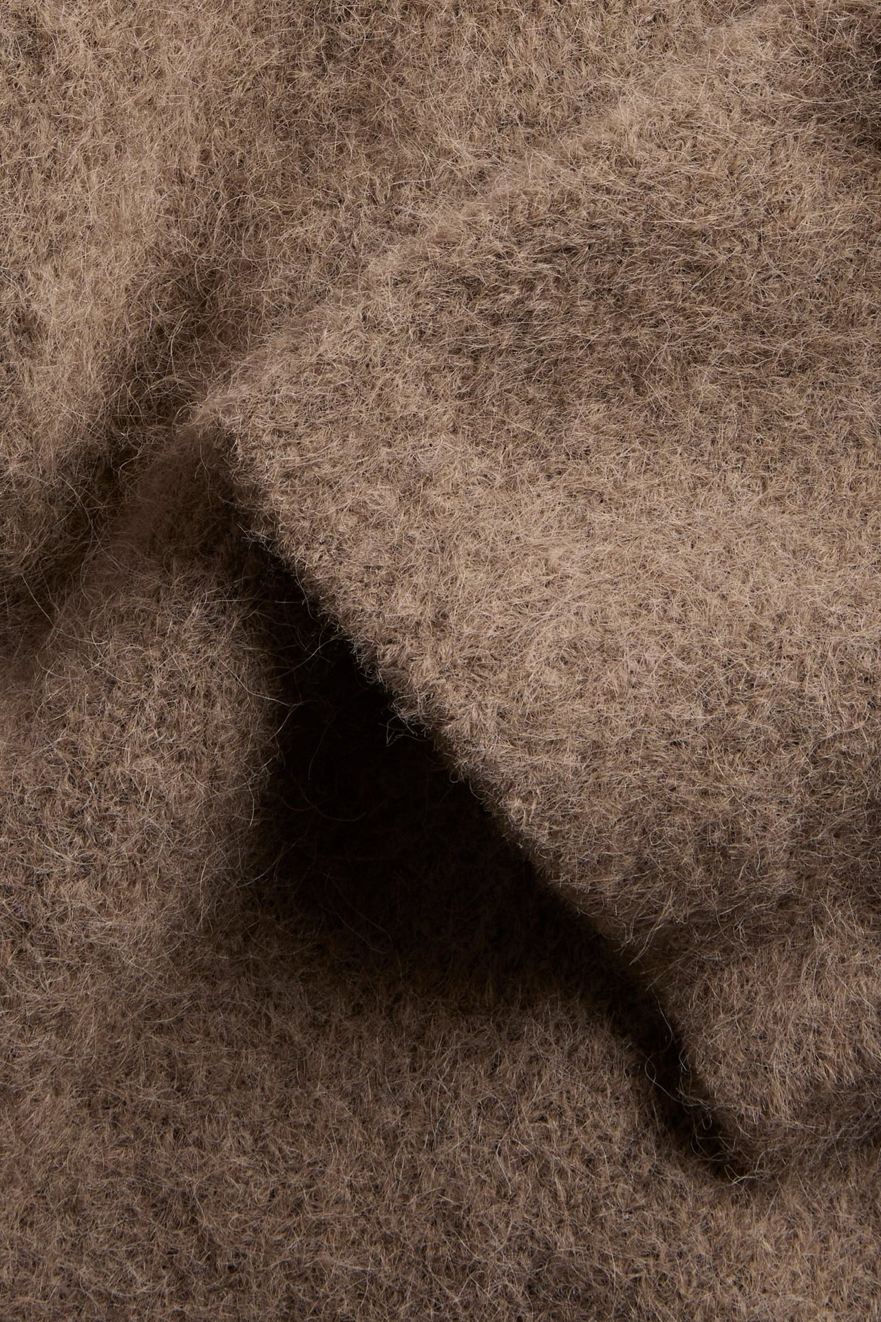 Närbild på brunt luddigt texturerat tyg med veck.