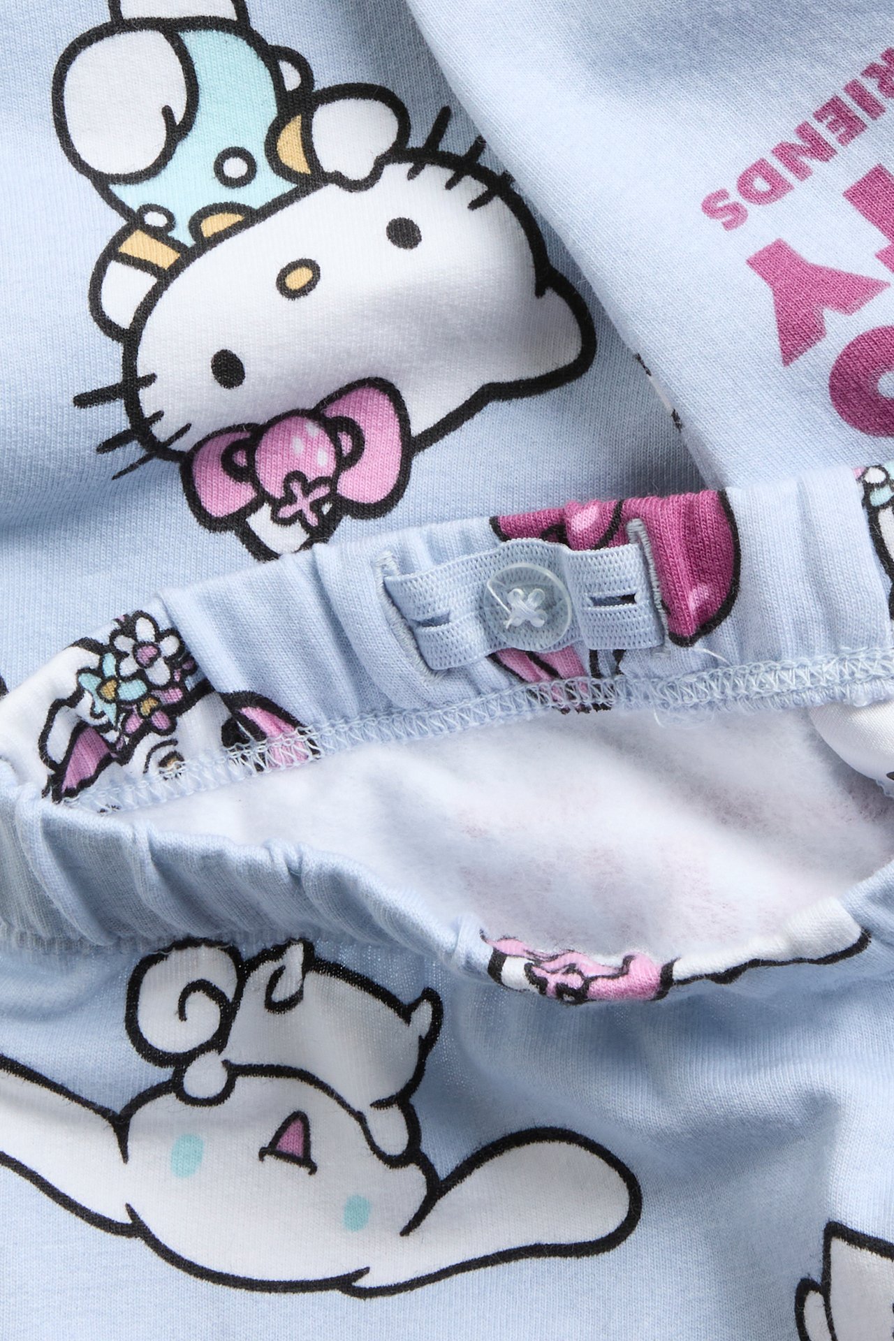 Zbliżenie jasnoniebieskich piżamowych spodni dziecięcych z nadrukiem Sanrio i regulowanym pasem.