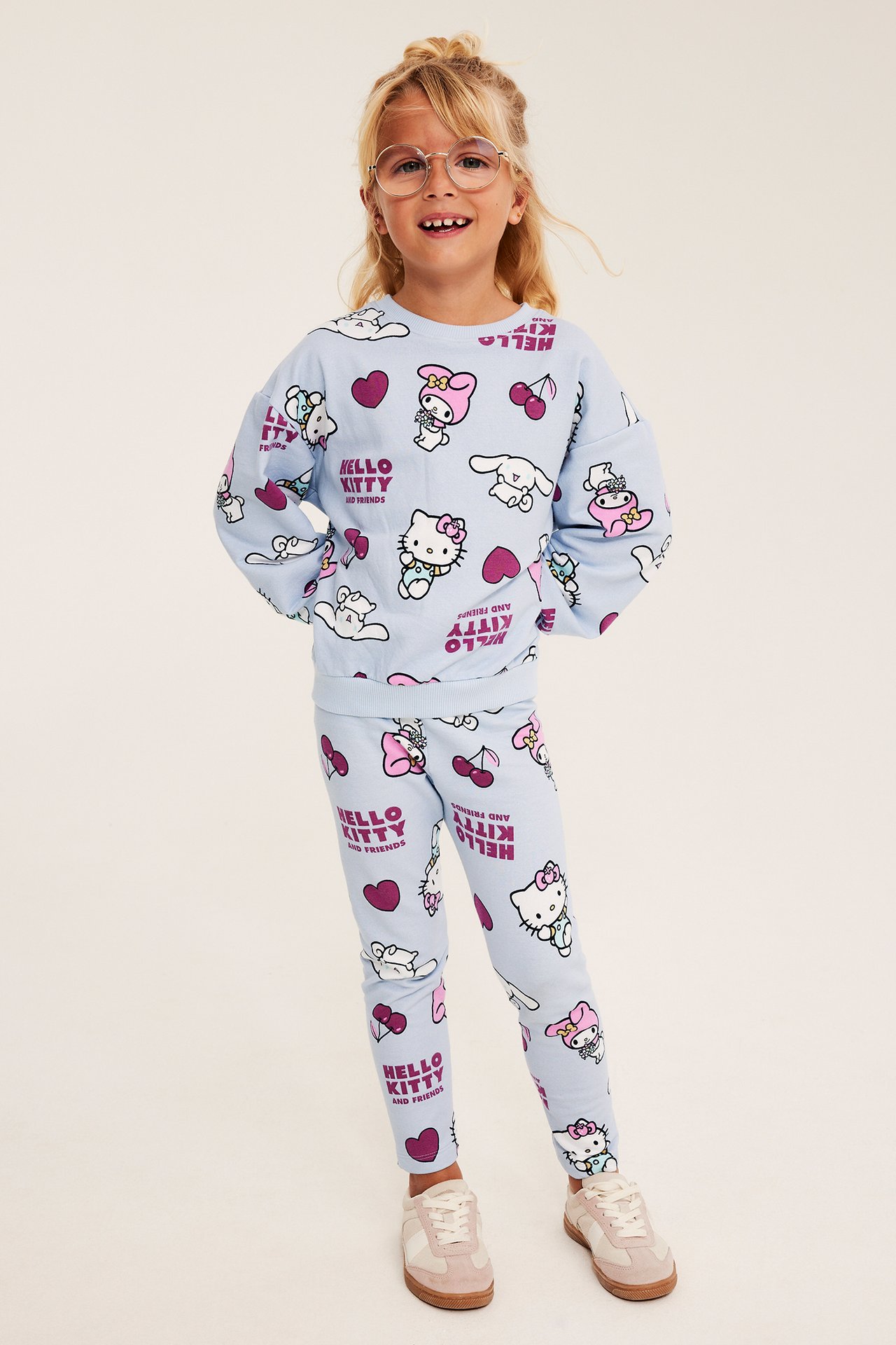Widok z przodu dziecka w jasnoniebieskiej bluzie z nadrukiem Hello Kitty and Friends i pasujących legginsach.