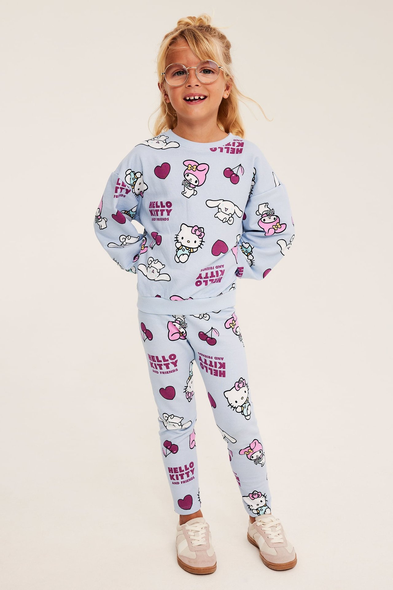 Widok z przodu dziecka w jasnoniebieskiej bluzie z nadrukiem Hello Kitty and Friends i pasujących legginsach.