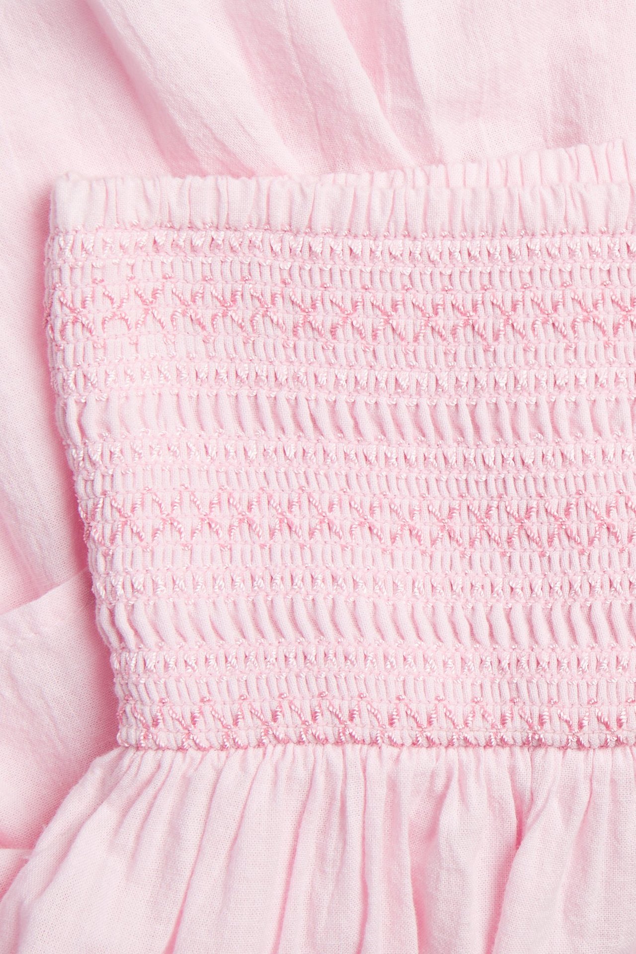 Lähikuva vaaleanpunaisesta röyhelöhameesta, jossa on yksityiskohtainen rypytetty vyötärönauha.