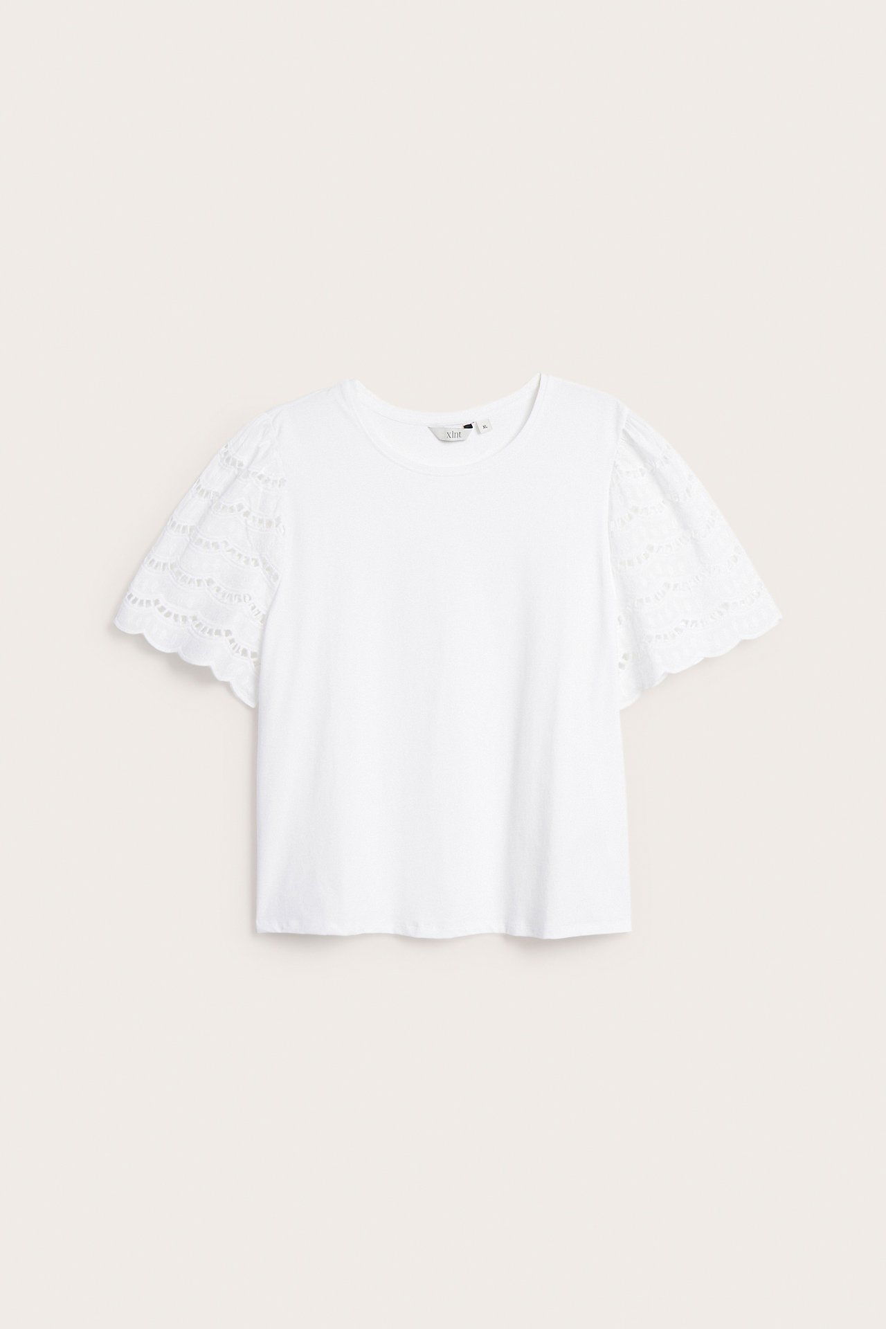 Edestä valkoinen naisten lyhythihainen toppi, puffatut broderie anglaise -hihat ja pyöreä kaula-aukko.