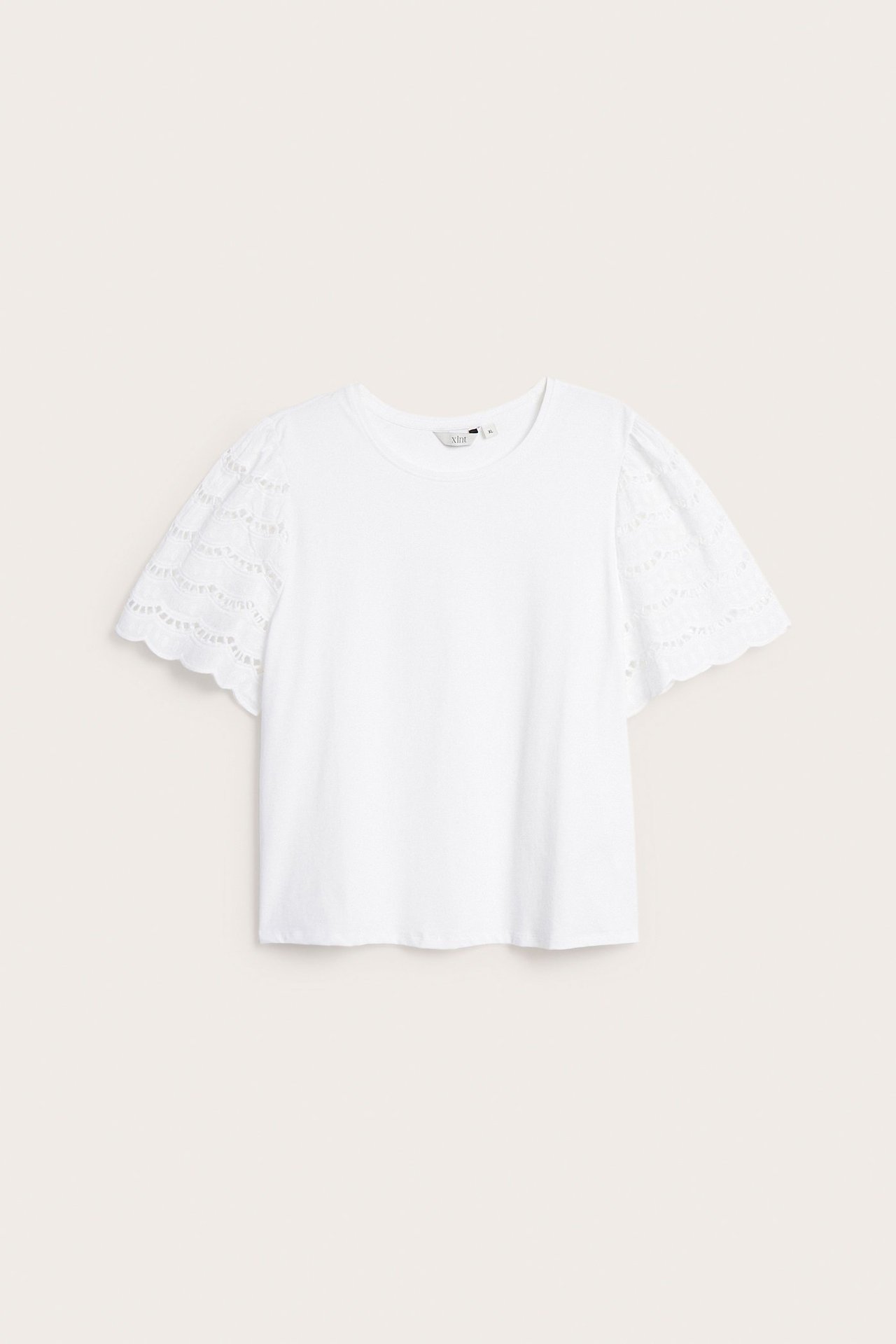 Edestä valkoinen naisten lyhythihainen toppi, puffatut broderie anglaise -hihat ja pyöreä kaula-aukko.