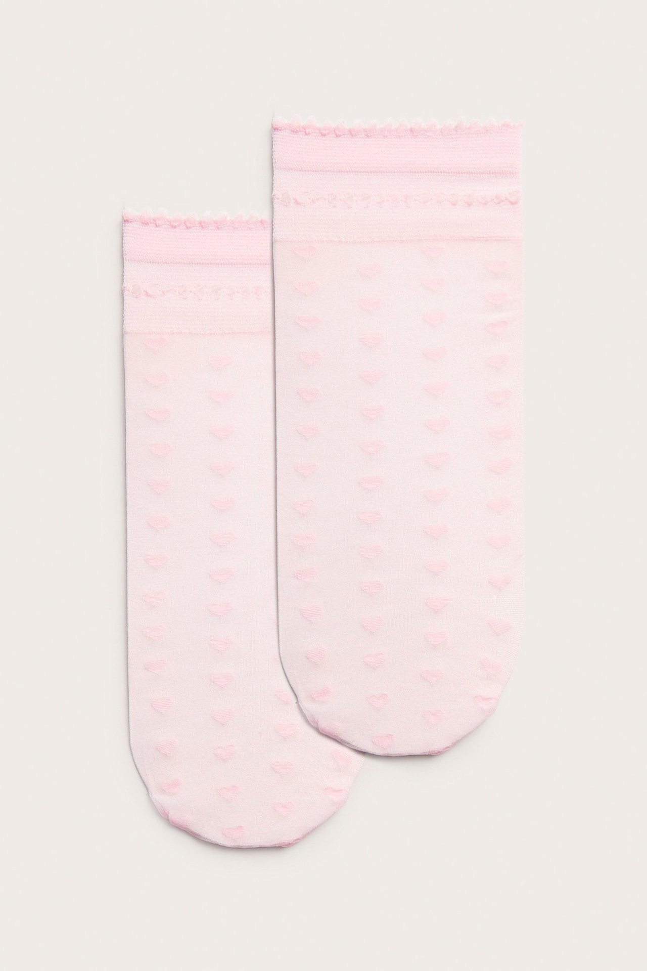Forfra, to lyserosa gjennomsiktige ankelsokker med hjertemønster og delikate rysjekanter.