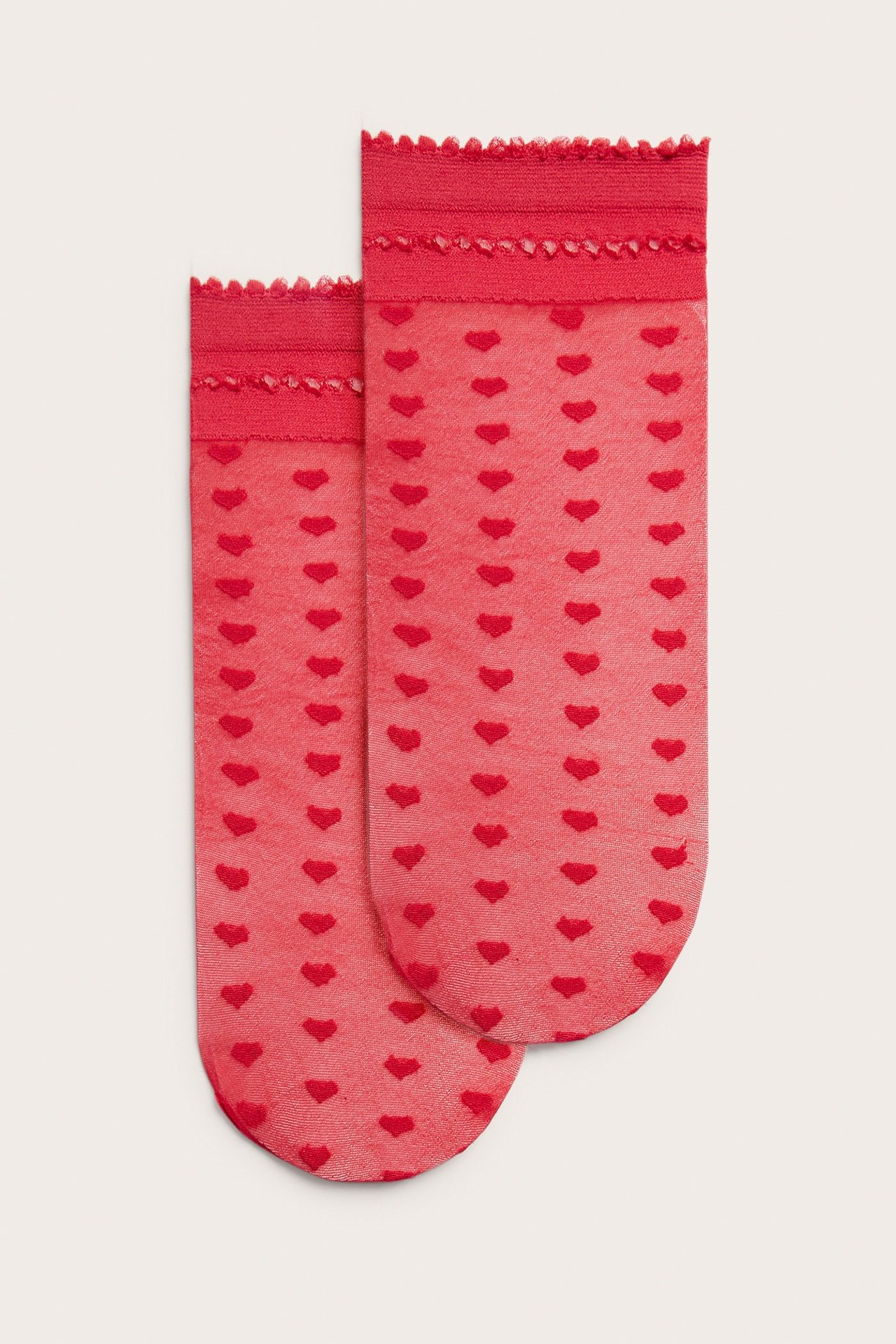 Frontvisning av to røde tynne damestrømper med hjertemønster og volangkant.