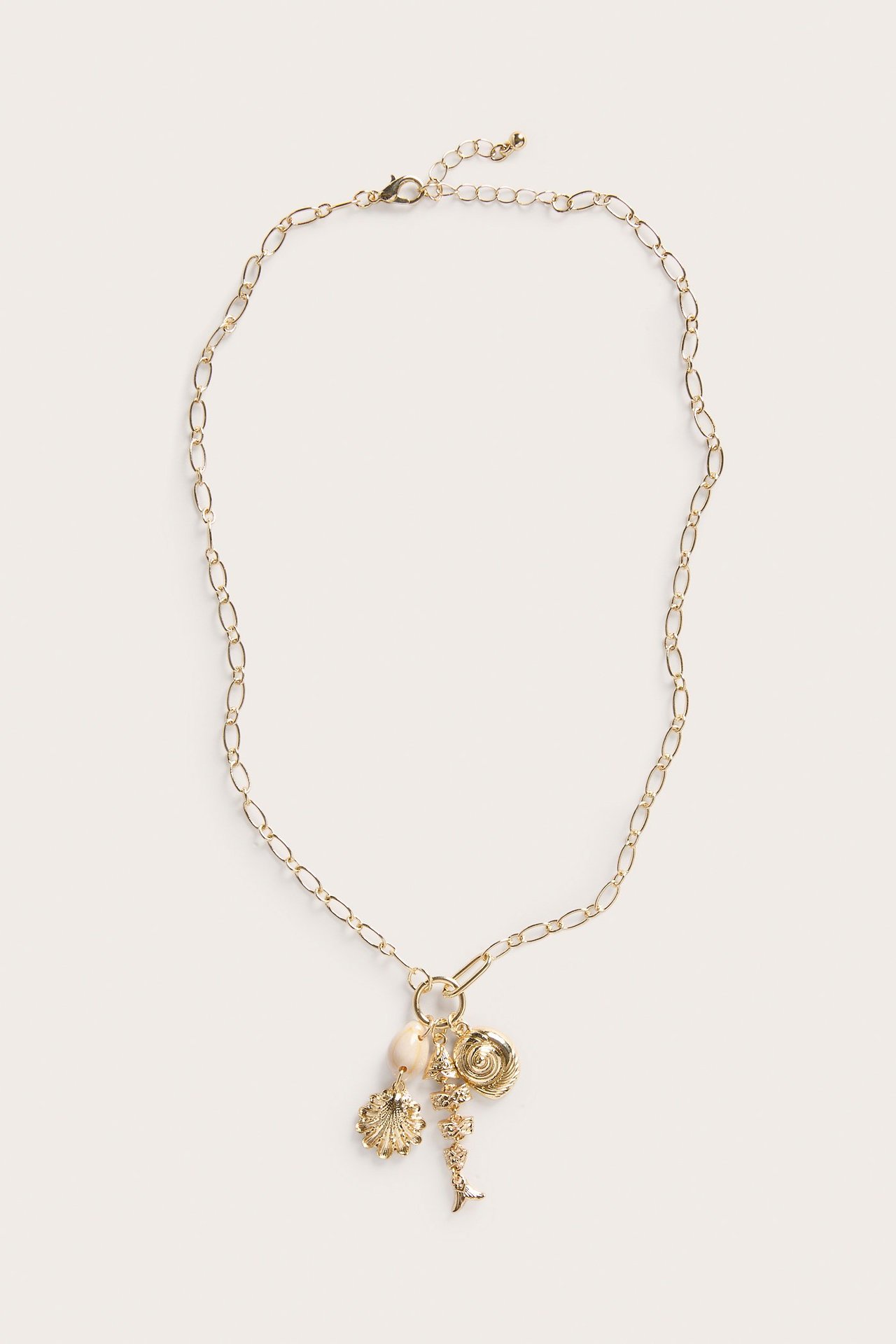 Koko kuva kullanvärisestä metallikaulakorusta, jossa on ovaalilenkkiketju ja useita simpukka- ja spiraaliriipuksia.