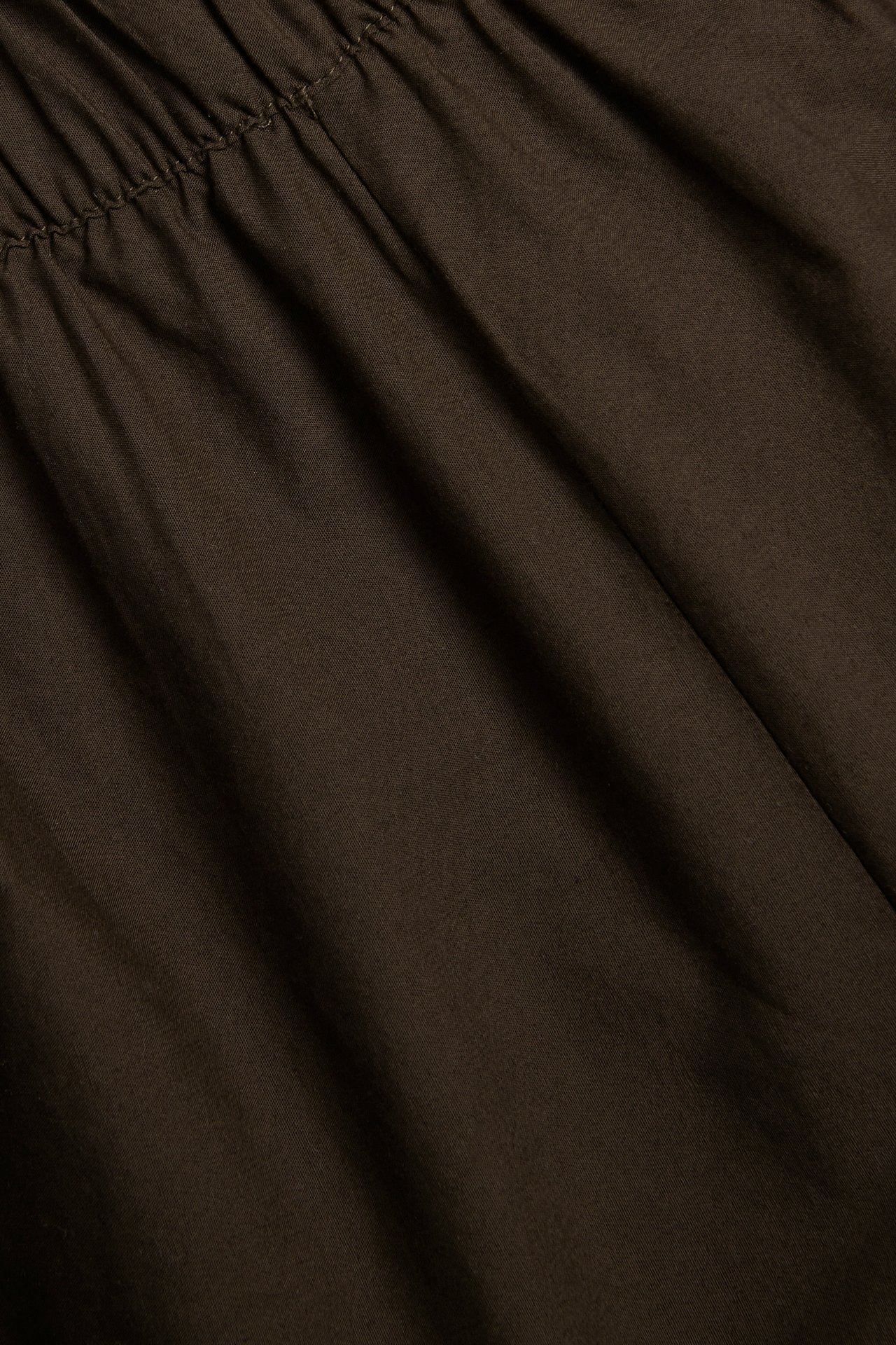 Nærbilde av mørkebrune bomullspoplin-shorts, som viser en rynket elastisk midje.