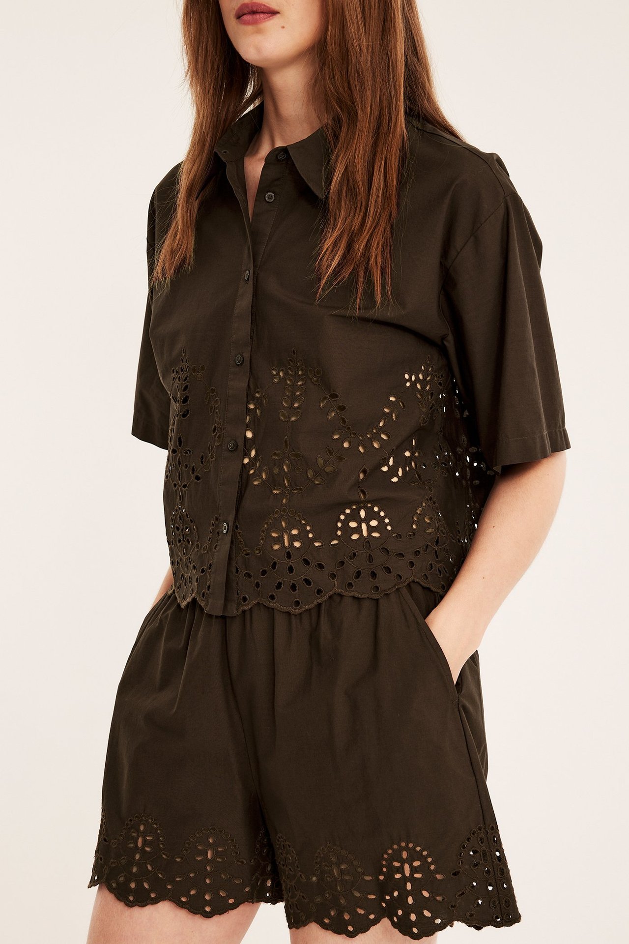 Edestä: Nainen tummanruskeissa puuvillapopliinishortseissa, joissa pitsireunus, ja yhteensopiva lyhythihainen paita.