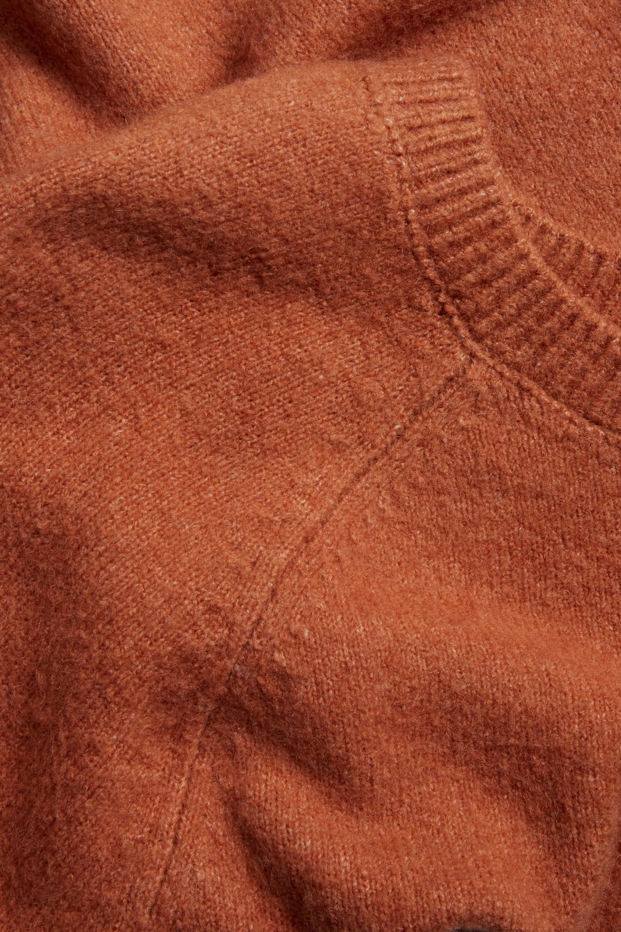Zbliżenie na czerwony melanżowy, oversize'owy, dziergany T-shirt z prążkowanym dekoltem.