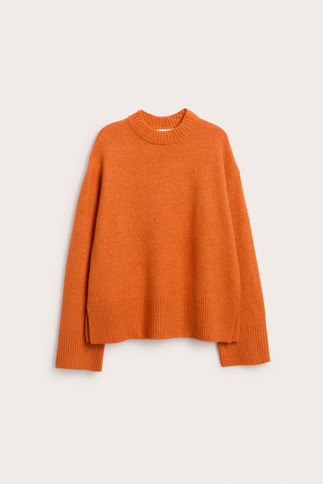 Frontvy av en orange melerad stickad pullover med rundhals och ribbad nederkant.
