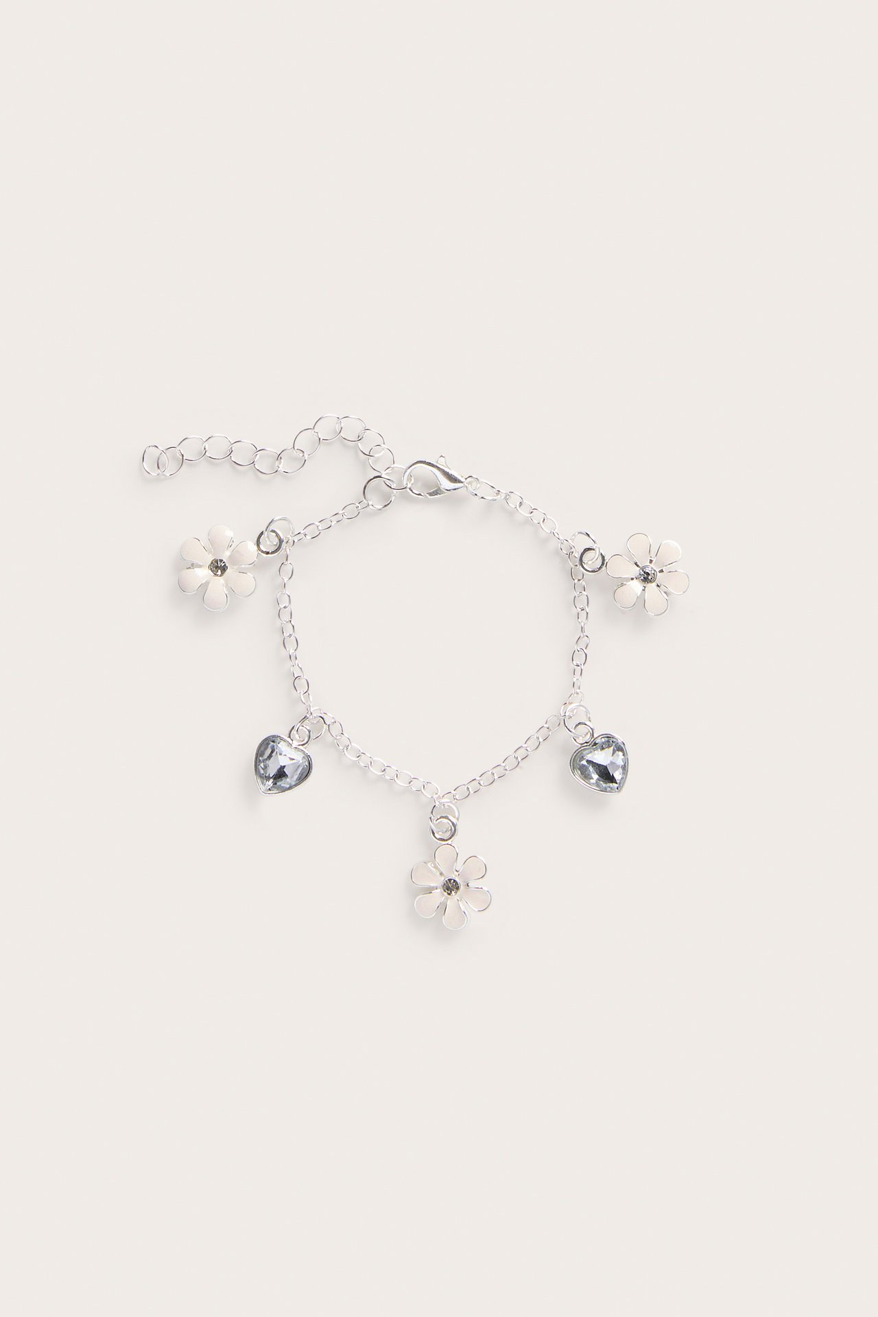 Uppifrån sett silverfärgat metallarmband med karbinhake, med vita blom- och ljusblå hjärtberlocker.