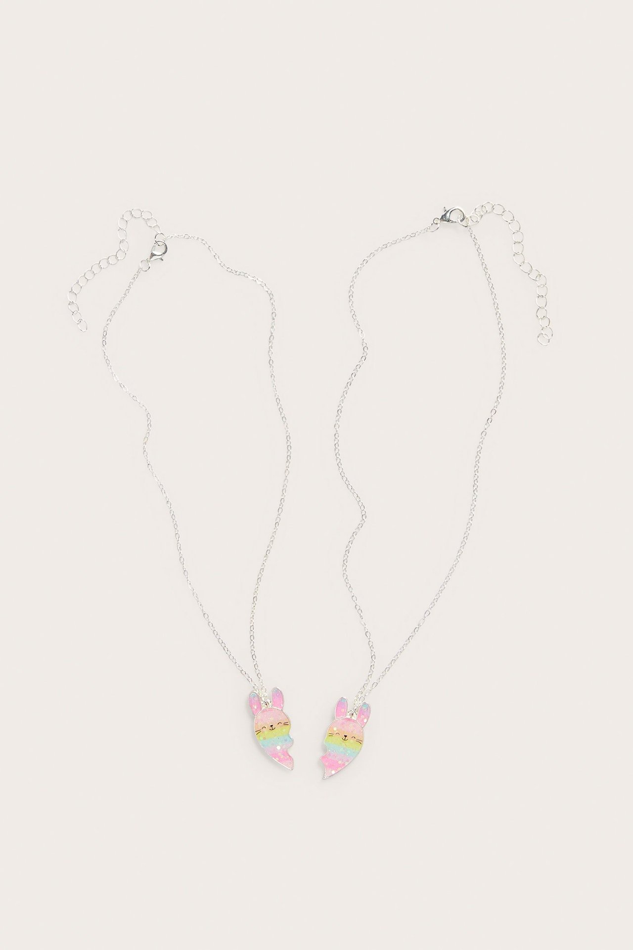 Forside av to sølv vennskapshalskjeder med regnbuestripete, glitrende halvkanin-anheng og karabinkroklåser.