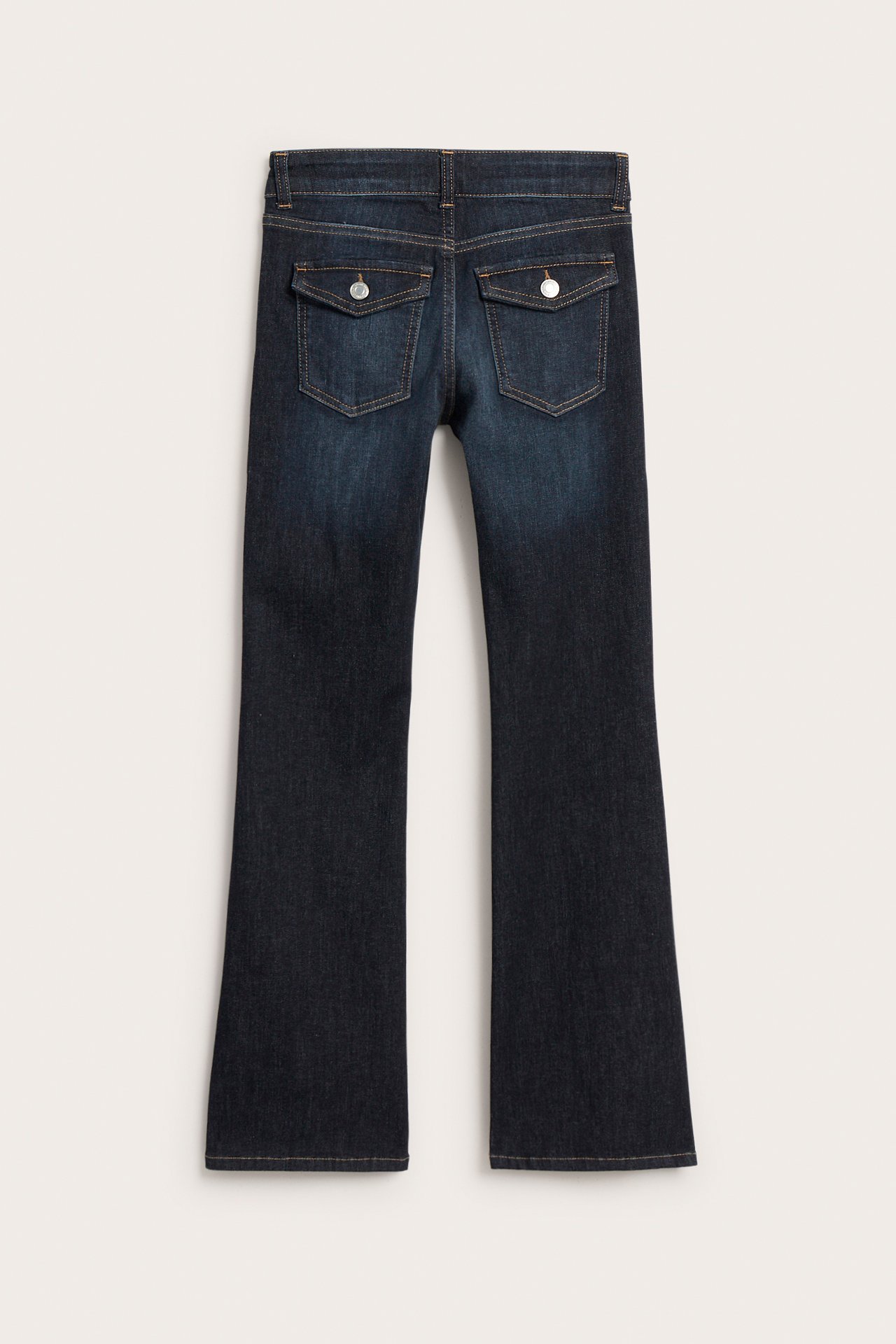 Bakifrån mörka bootcut-jeans med två ficklock och silverfärgade knappar.
