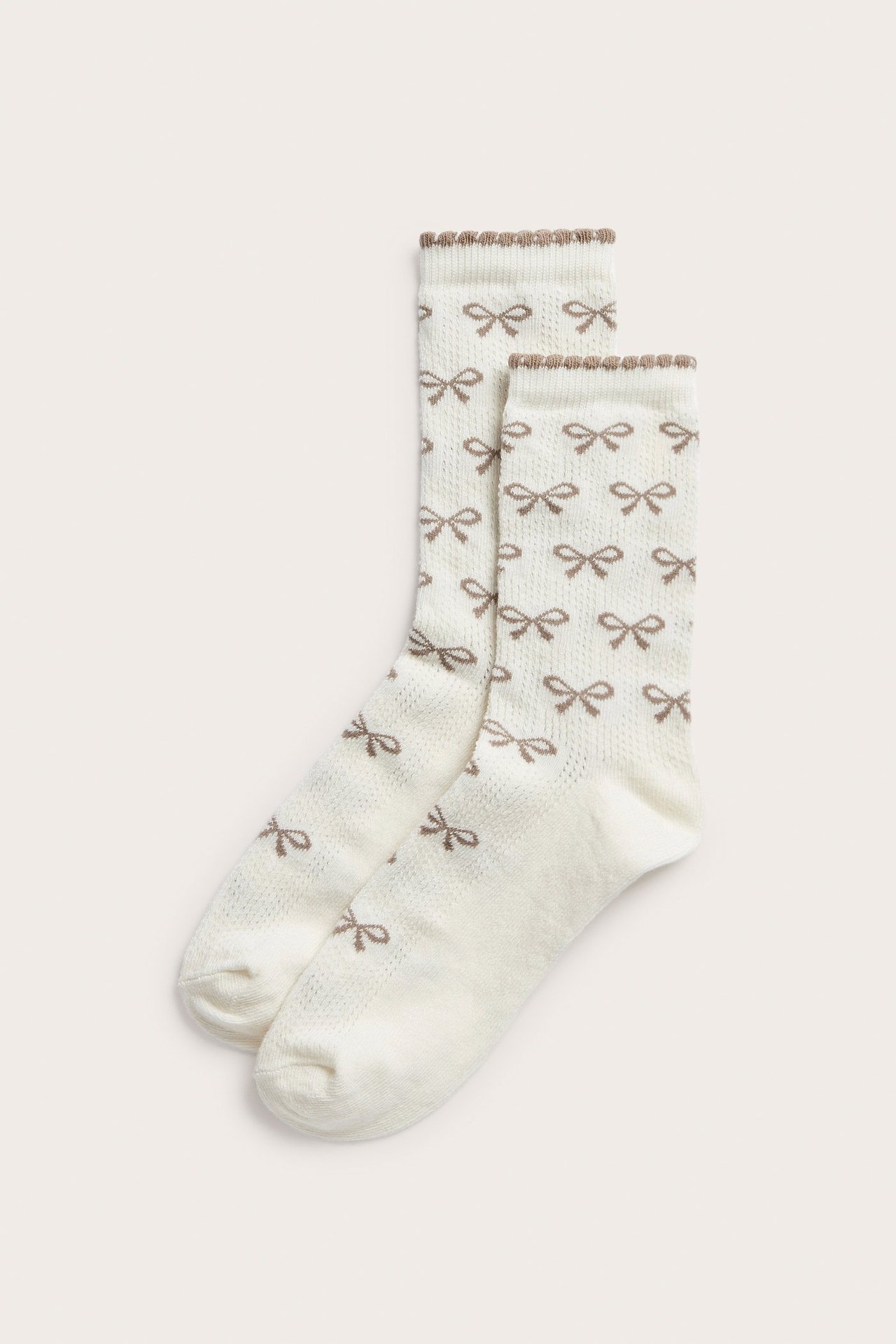 Forfra, et par beige pointellestrømper med brunt sløyfemønster og picotkant.