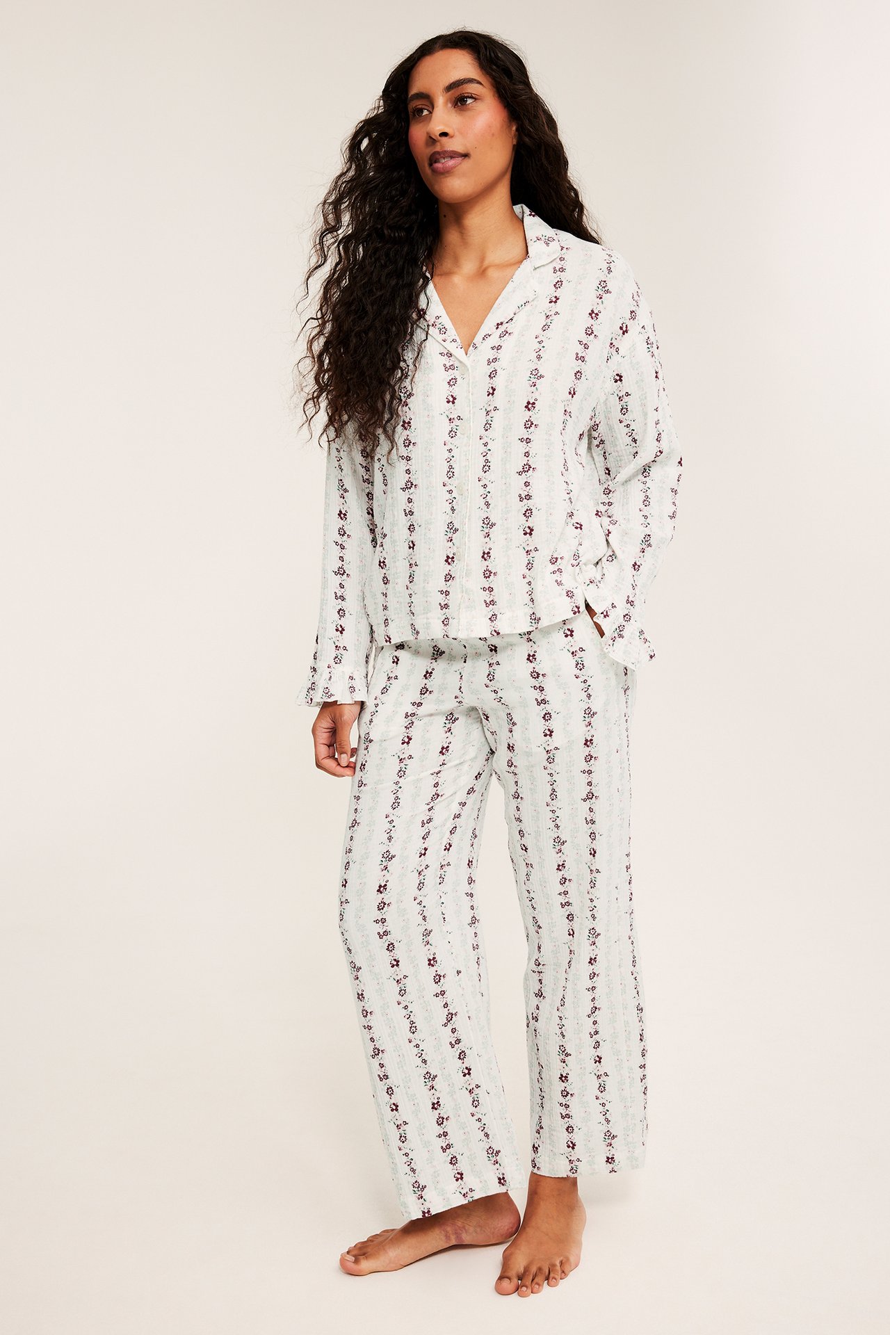 Framifrån: kvinna i ljusgrå blommigrandig pyjamas.