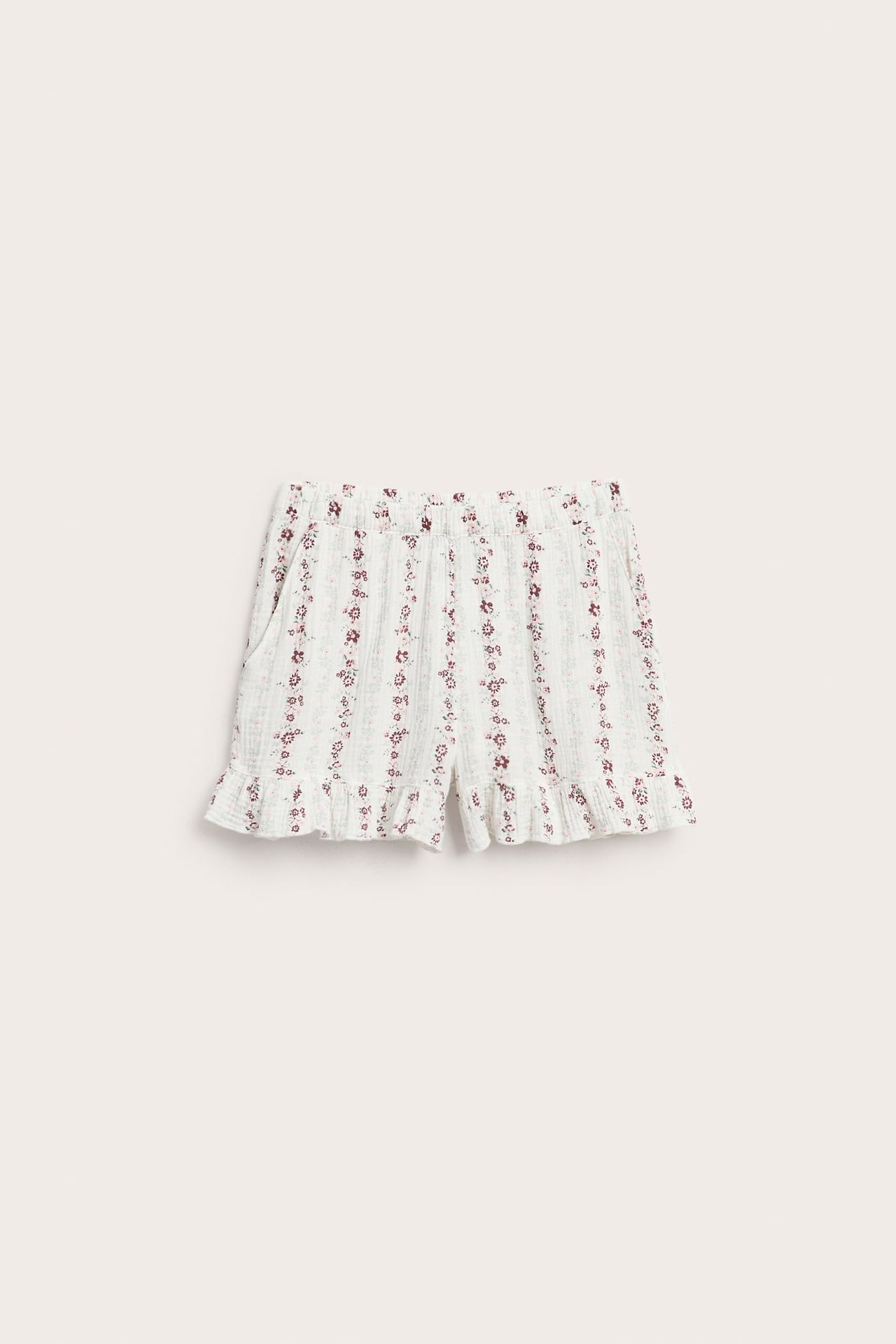 Framifrån, vita blommiga shorts med resår i midjan och volangkant.