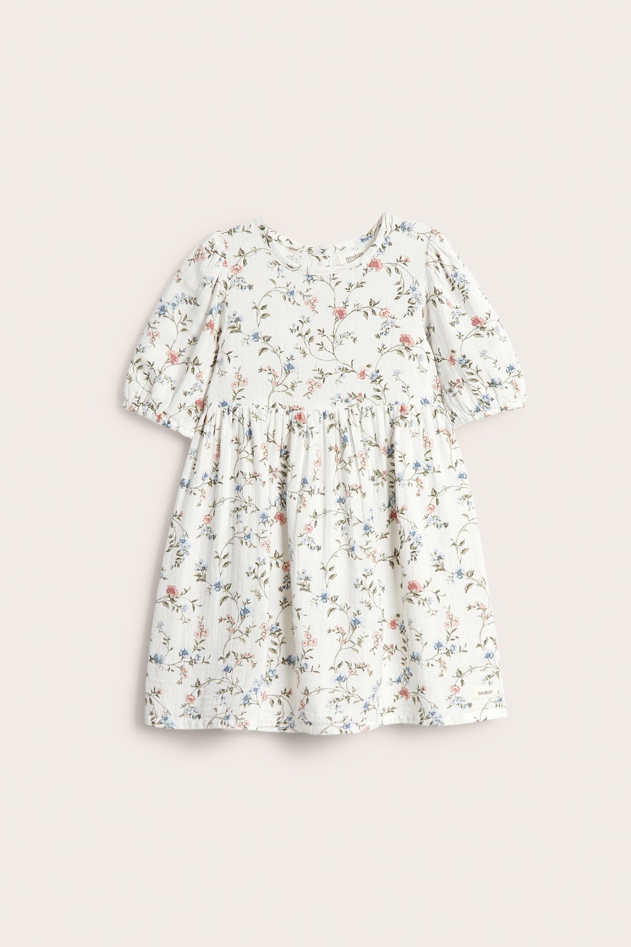 Frontvisning av en offwhite blomsterkjole for barn med korte puffermer og rynket midje.