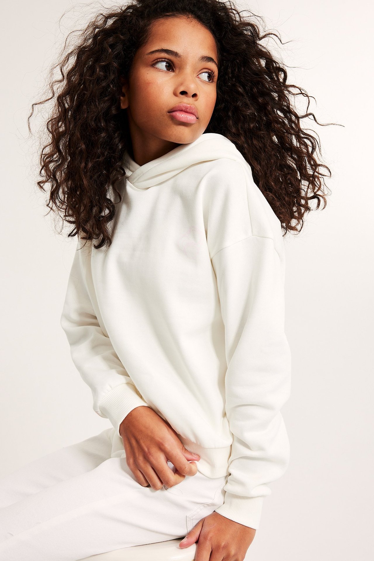 Widok z przodu dziecka ubranego w kremową bluzę z kapturem i pasujące spodnie.