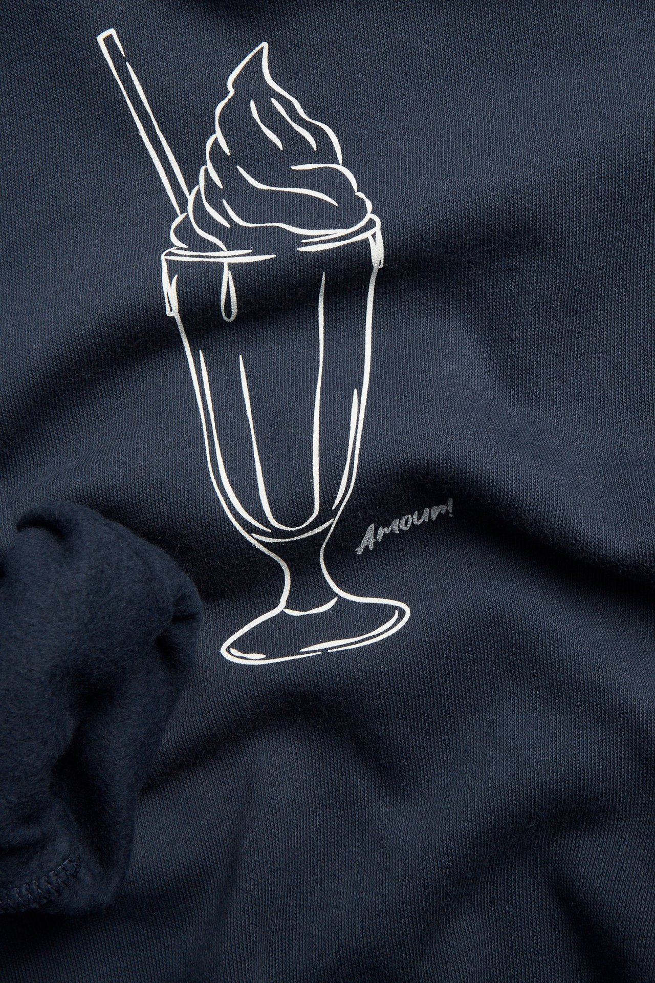 Zbliżenie na przód niebieskiej dziecięcej bluzy z kapturem z białym nadrukiem milkshake'a i 'Amour!'.