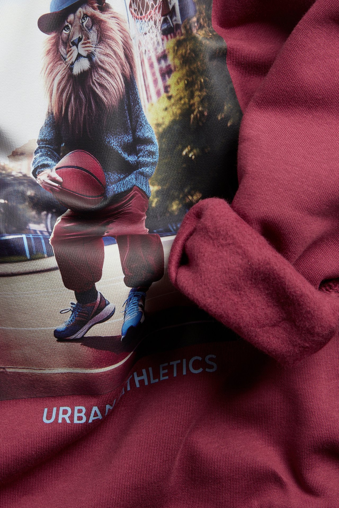 Zbliżenie na bordową bawełnianą bluzę z czesanym wnętrzem i dużym nadrukiem lwa.