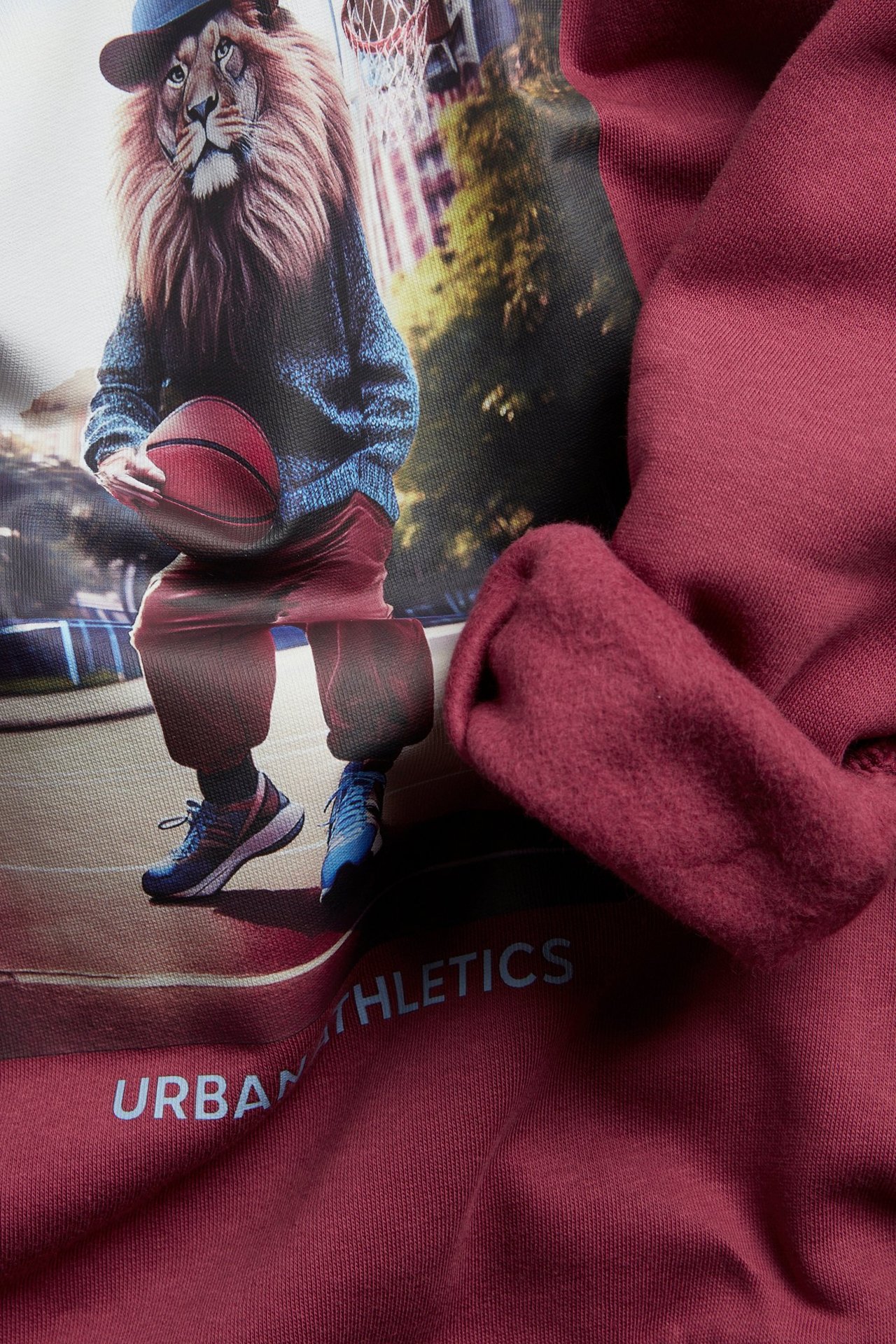 Zbliżenie na bordową bawełnianą bluzę z czesanym wnętrzem i dużym nadrukiem lwa.