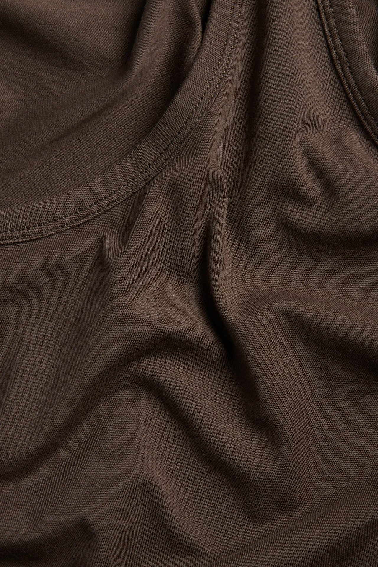 Zbliżenie brązowego materiału ze szwami i fałdami.