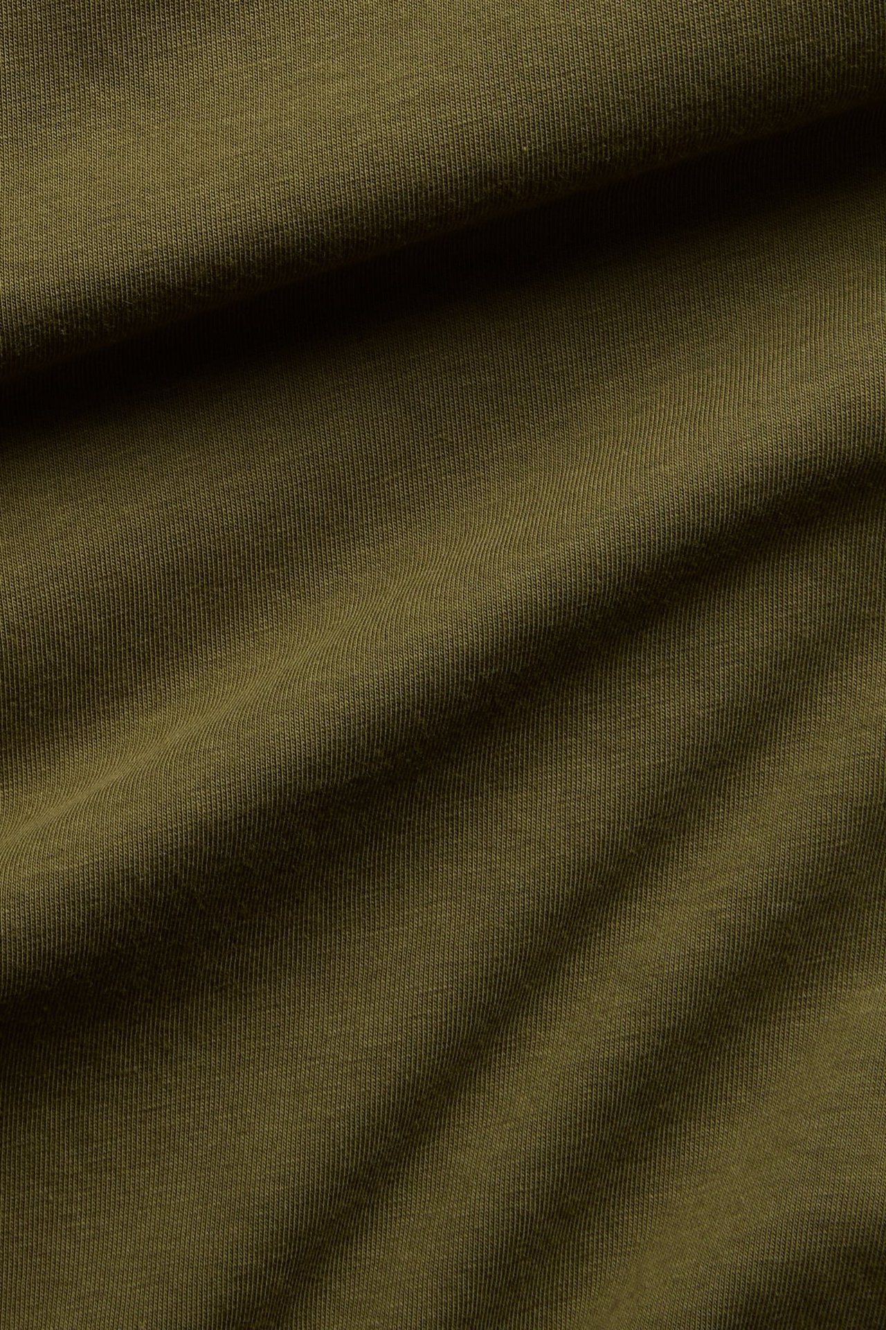 Närbild av khakigrön bomullsblandad jerseytyg, draperad med mjuka veck.