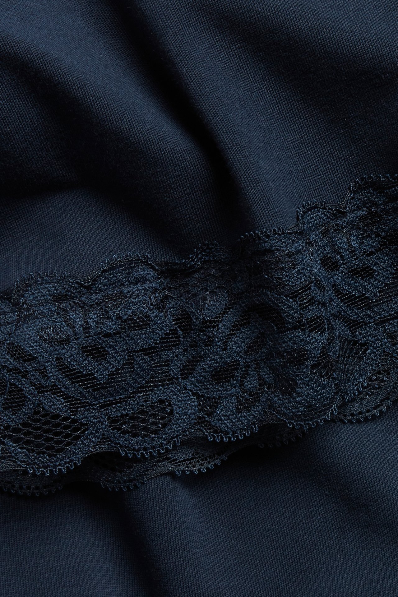 Zbliżenie niebieskiego topu na ramiączkach z delikatną koronkową lamówką.