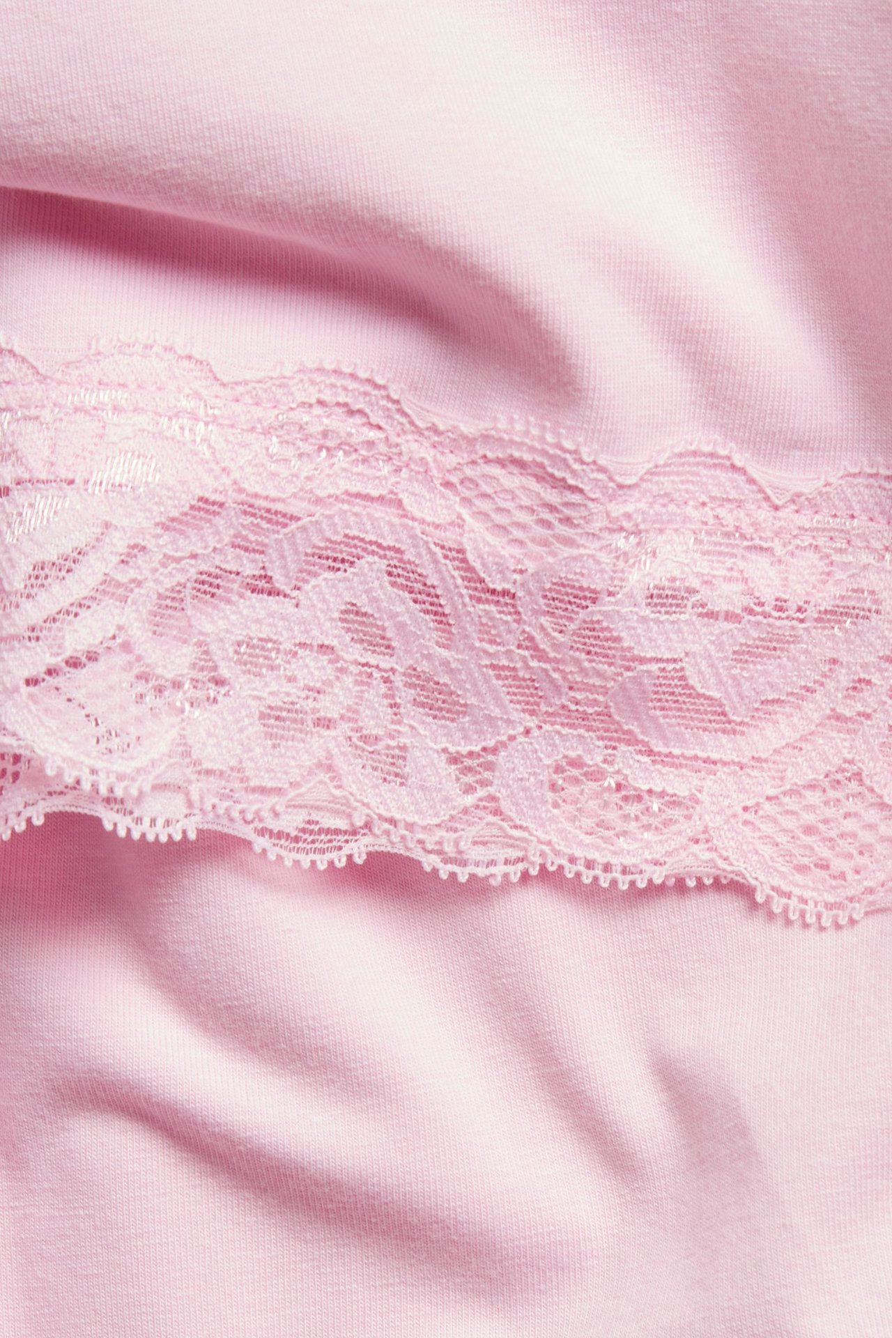 Zbliżenie na różowy top z dzianiny z delikatną koronkową lamówką wzdłuż brzegu.
