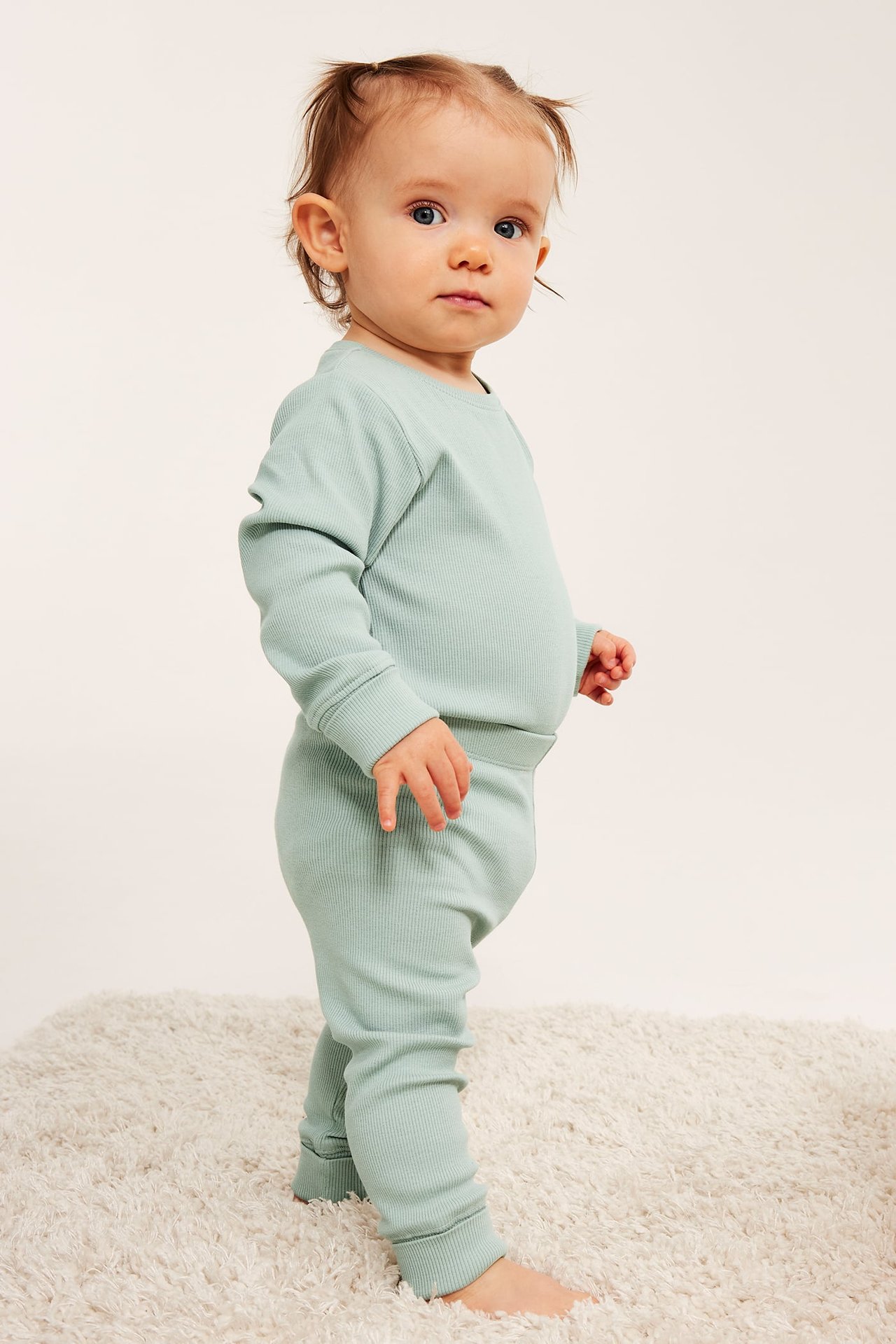 Sivukuva vauvasta yllään vaaleanvihreä pitkähihainen ribbipaita ja yhteensopivat leggingsit.