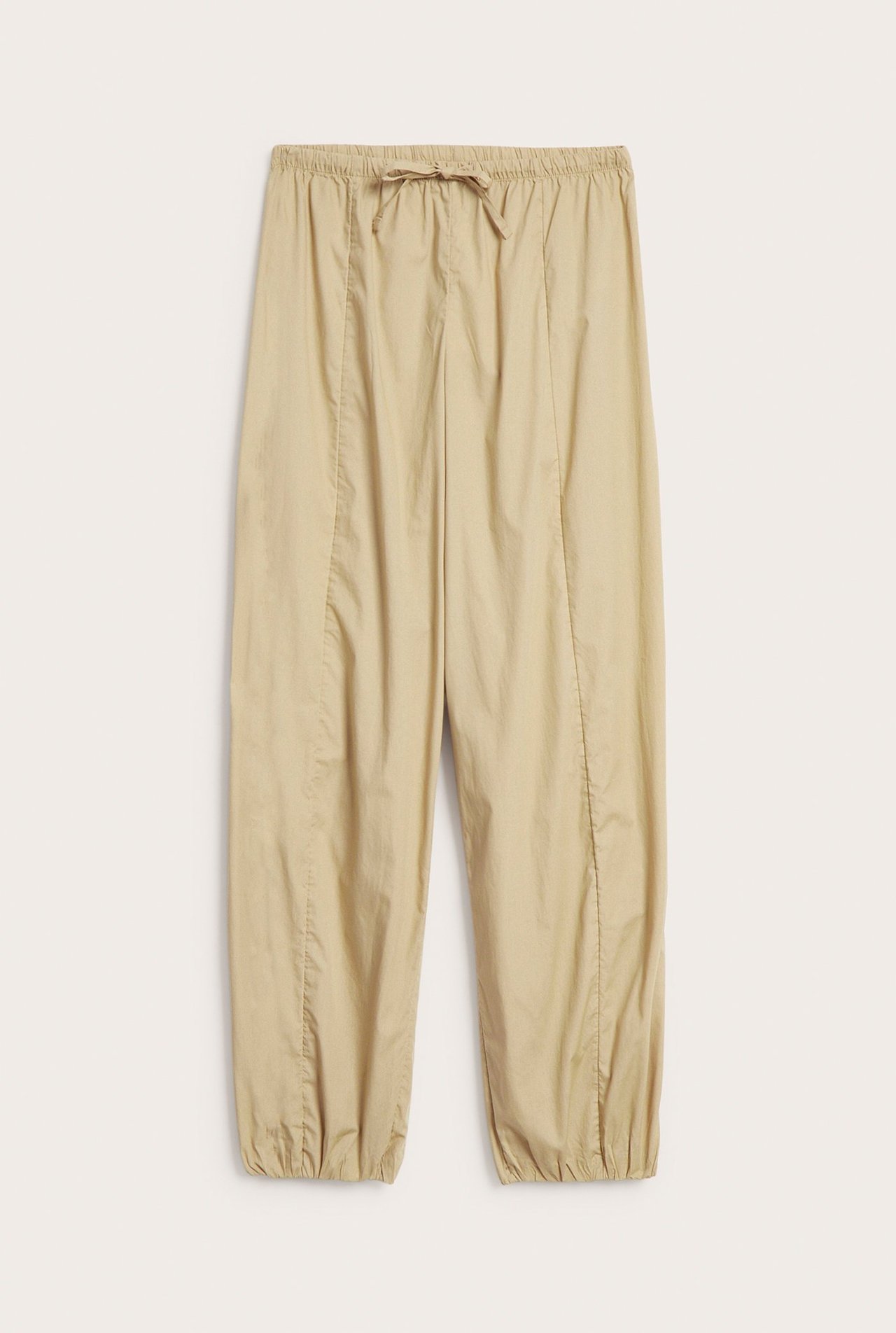 Frontvy av beige ballongbyxor i bomullspoplin med resårlinning, dragsko och elastisk benslut.