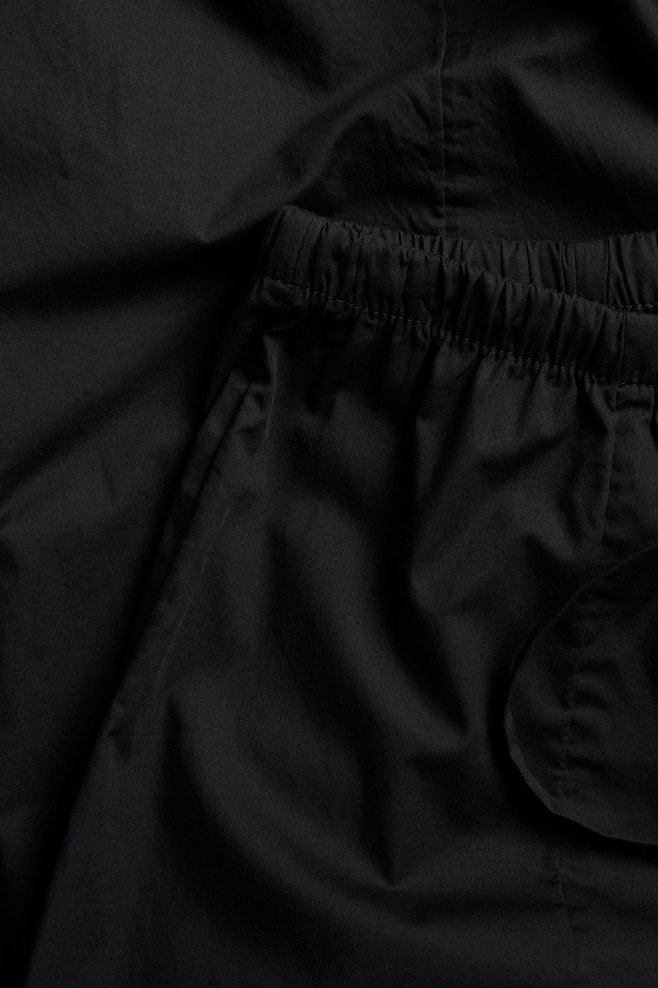 Närbild av svarta ballongbyxor i bomullspoplin med resår i midjan och dragsko.