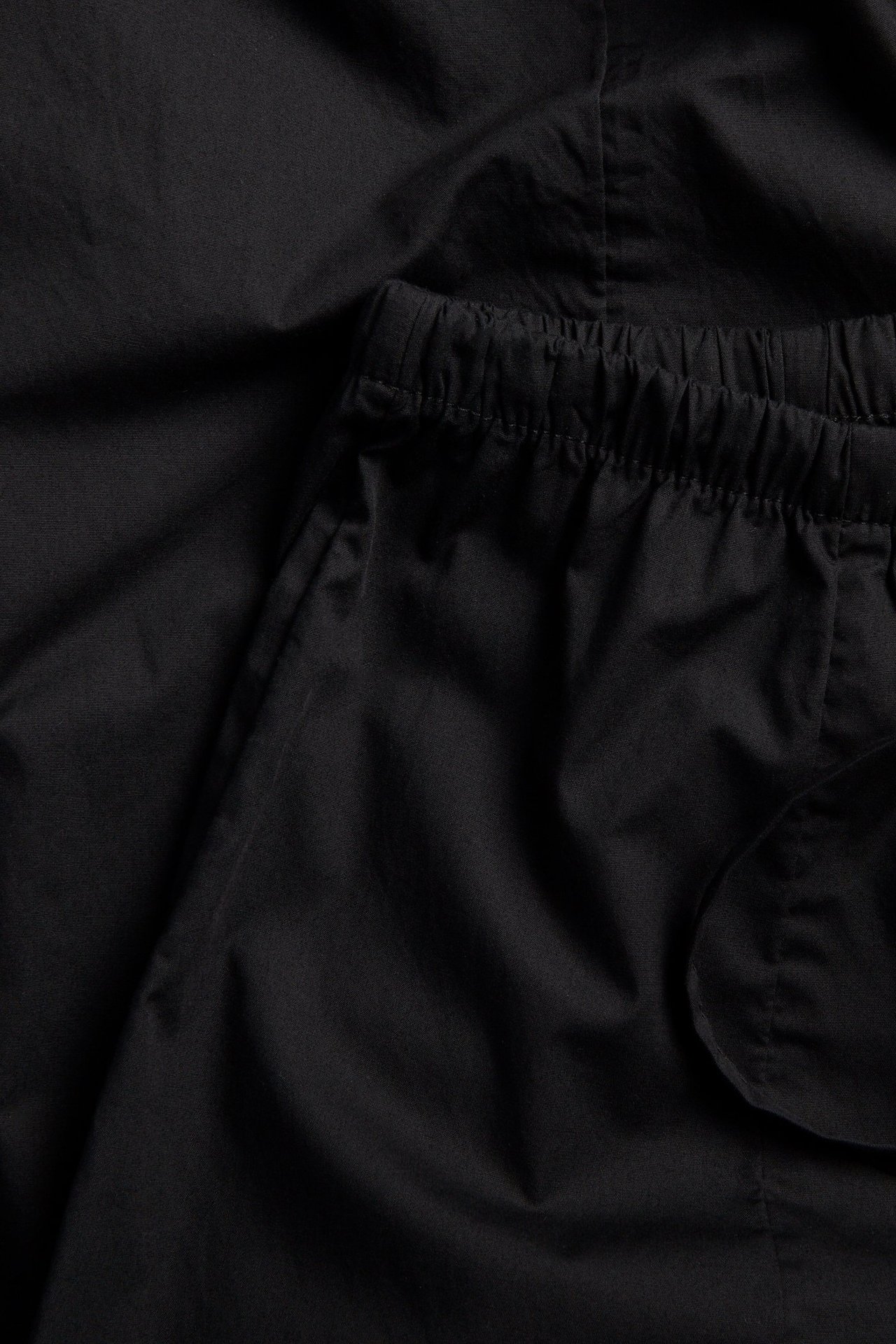 Zbliżenie na czarne bawełniane spodnie balonowe z elastyczną talią i sznurkiem.