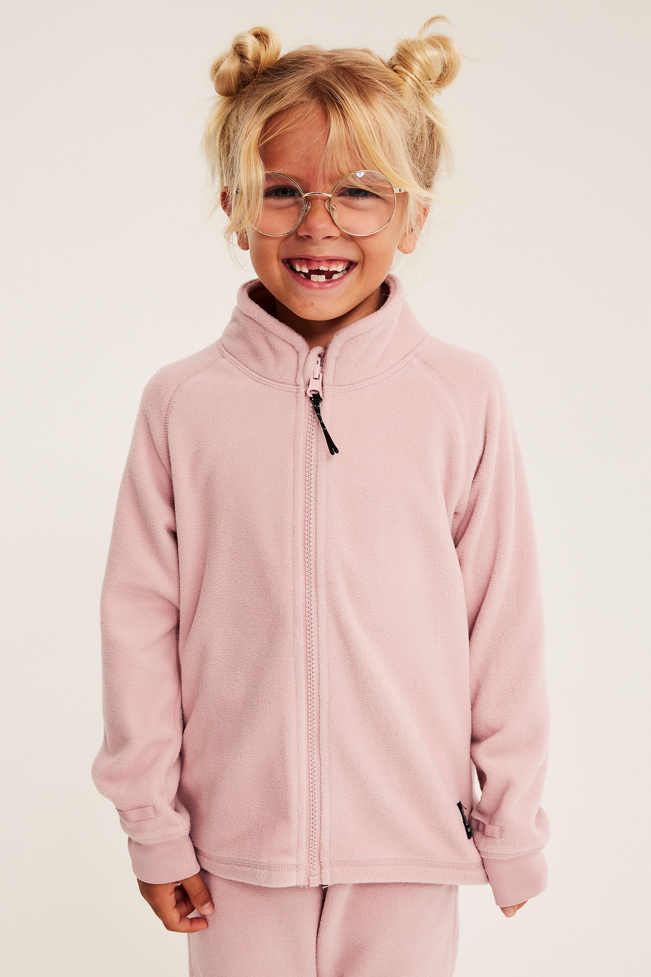 Framifrån, barn i rosa hel dragkedja fleecetröja och matchande fleecebyxor.