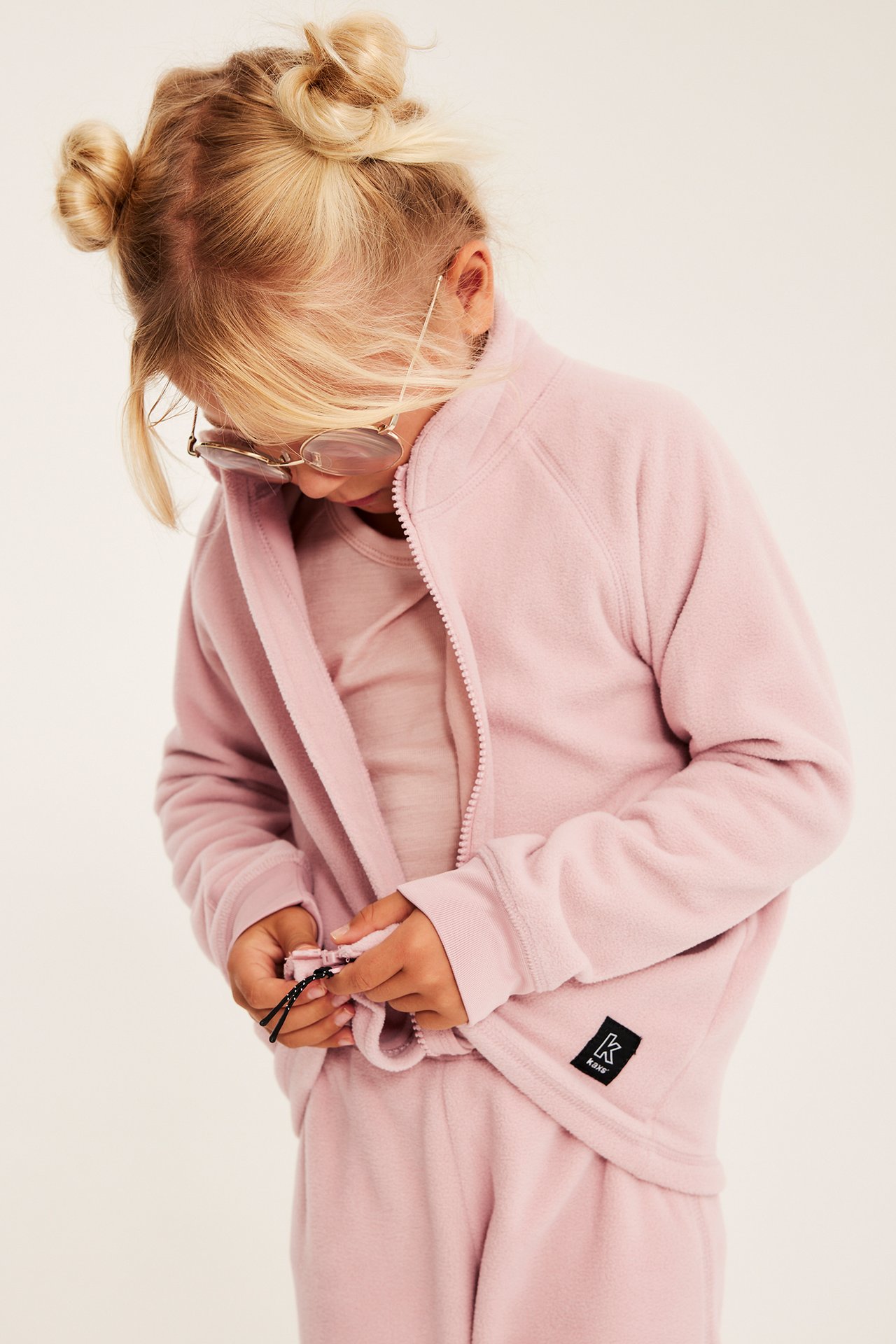 Framifrån, barn i rosa fleecejacka med dragkedja och matchande sweatpants.