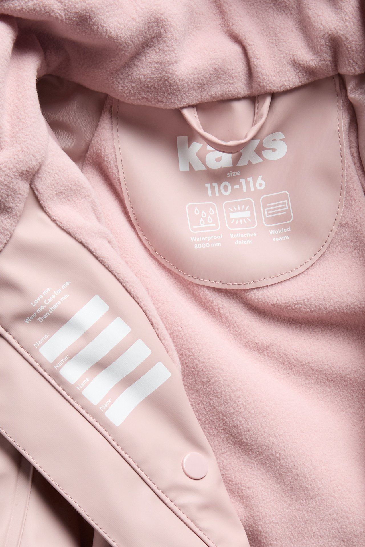 Nærbilde av en rosa barneregnsjakke, viser fleecefôr og produktetiketter.