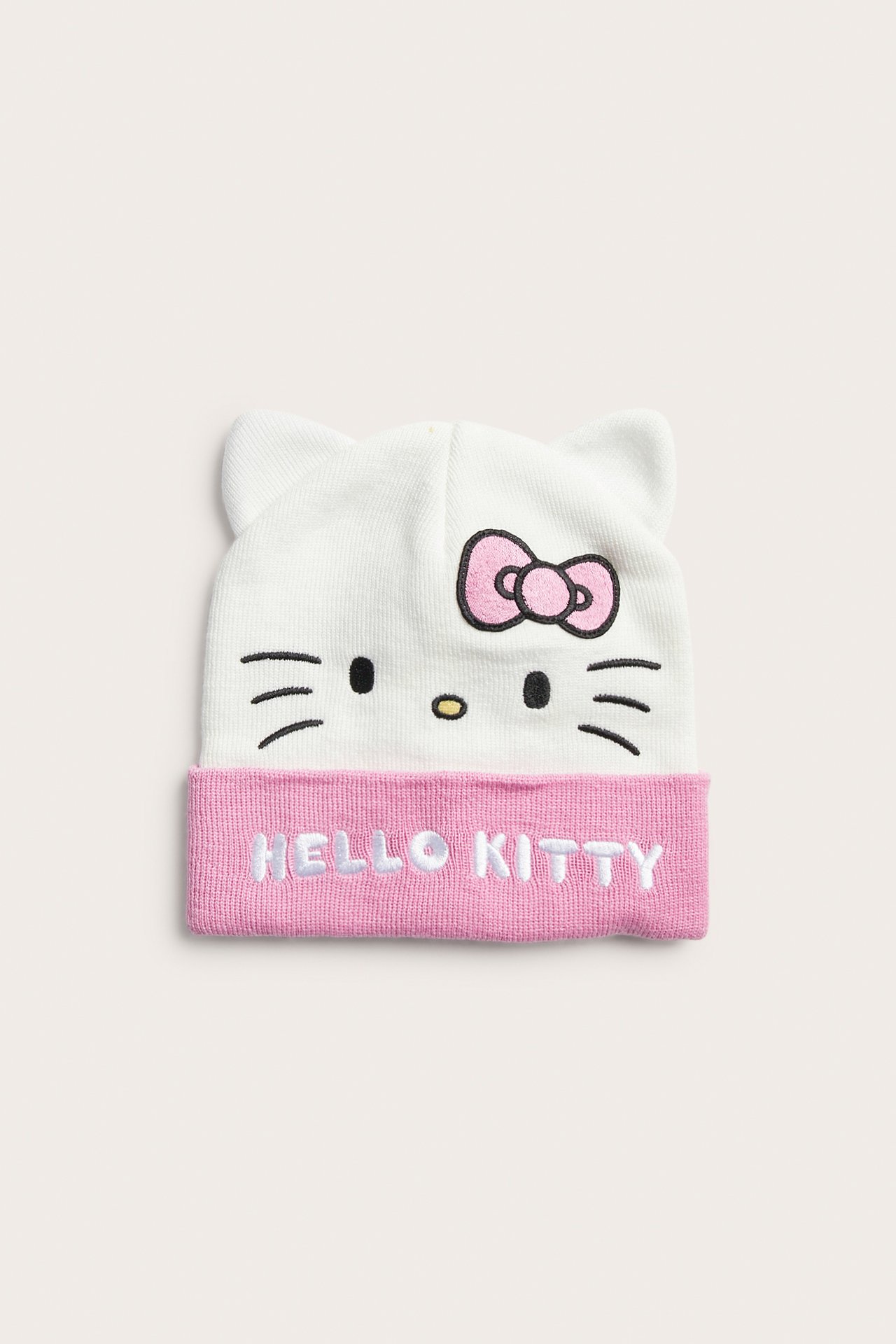 Widok z przodu białej i różowej dzianinowej czapki Hello Kitty z uszami kota.