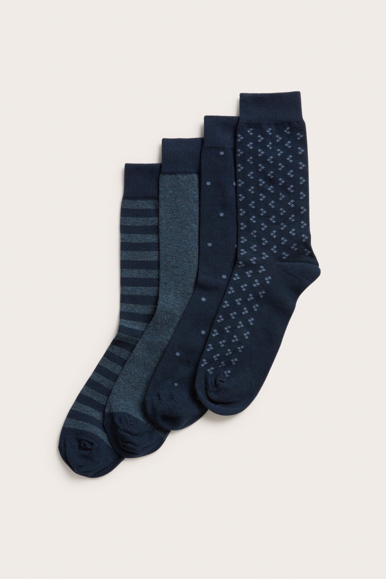 Ovenfra: Fire mørkeblå herresokker med blandede mønstre, inkludert striper, prikker og geometriske former.